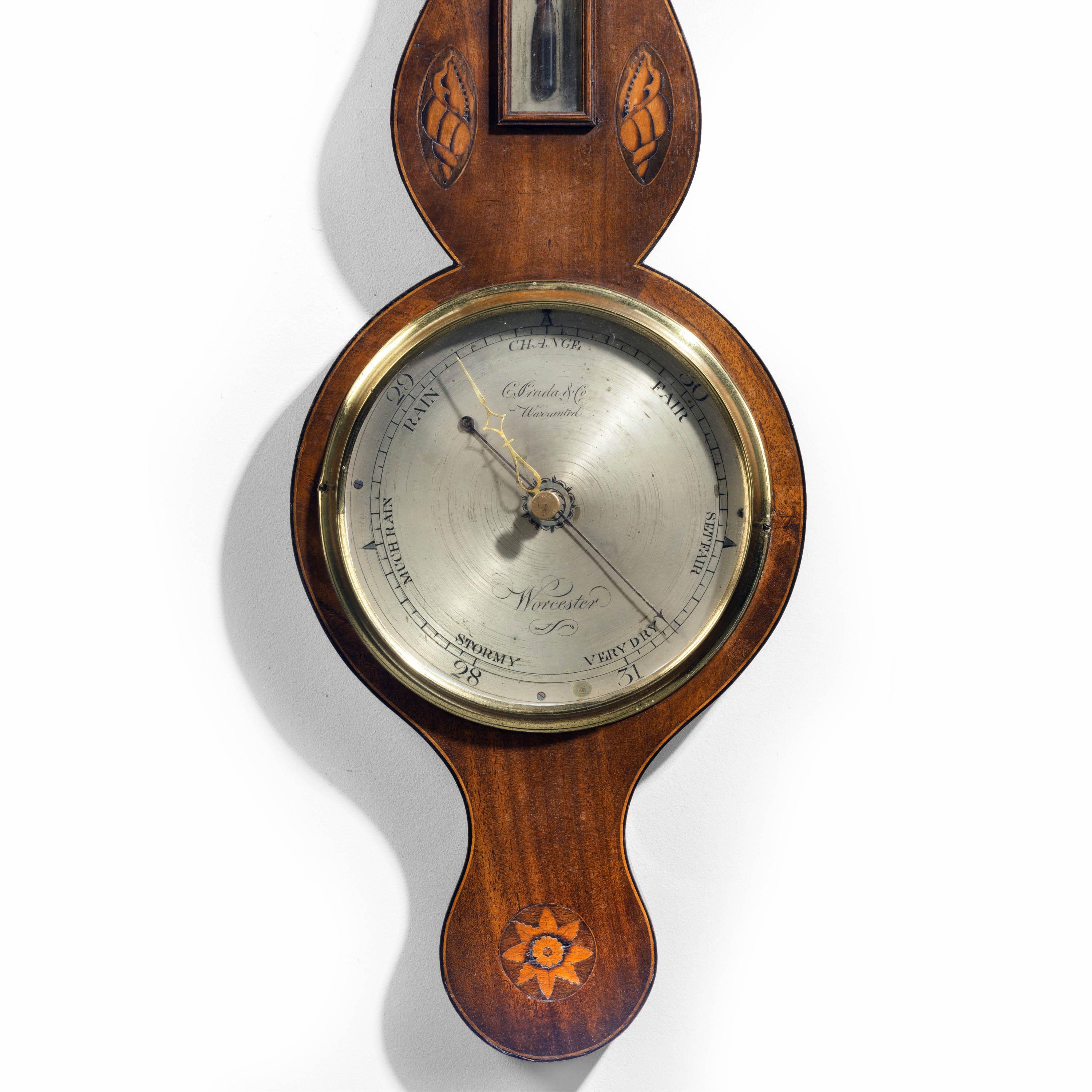 A most attractive George III period mahogany barometer by the Prada and Company of Worcester the finely made case with shells and double edging. A silver dial signed, incorporating a thermometer to the main body and original broken arched pediment