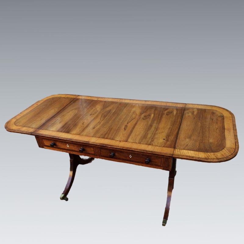 A most elegant George III rosewood sofa table with the fine figuration of the rosewood top and side flaps enhanced by satinwood cross-banding.  Satinwood and ebony stringing to all drawer fronts, with false drawers to the far side, all drawers