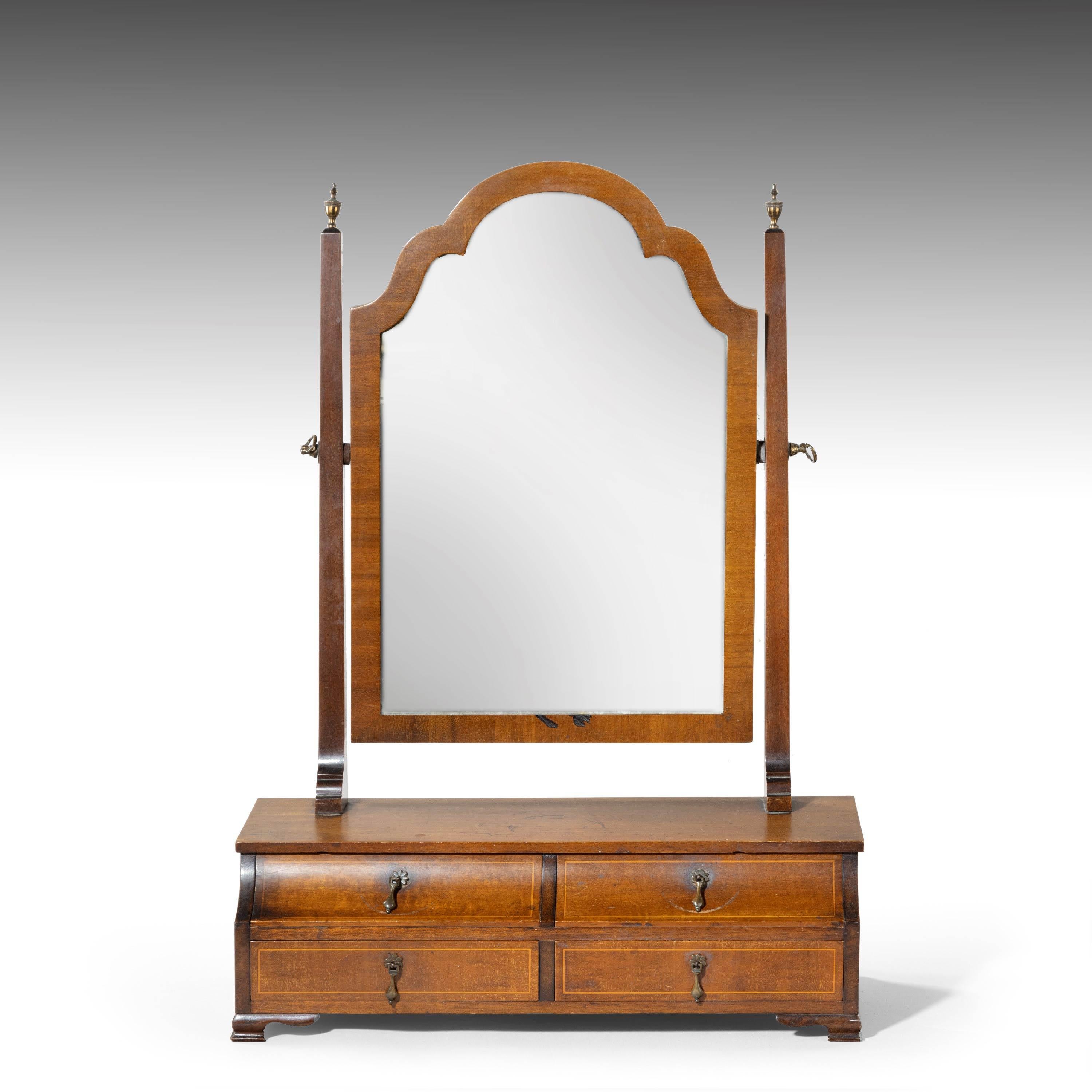 A most unusual mahogany framed mirror of Queen Anne design. A shaped top over a bank of four drawers. The top drawers with cavetto molded fronts. Very fine quality oak lined drawers. Original pendant and rather unusual brass drop handles.
 