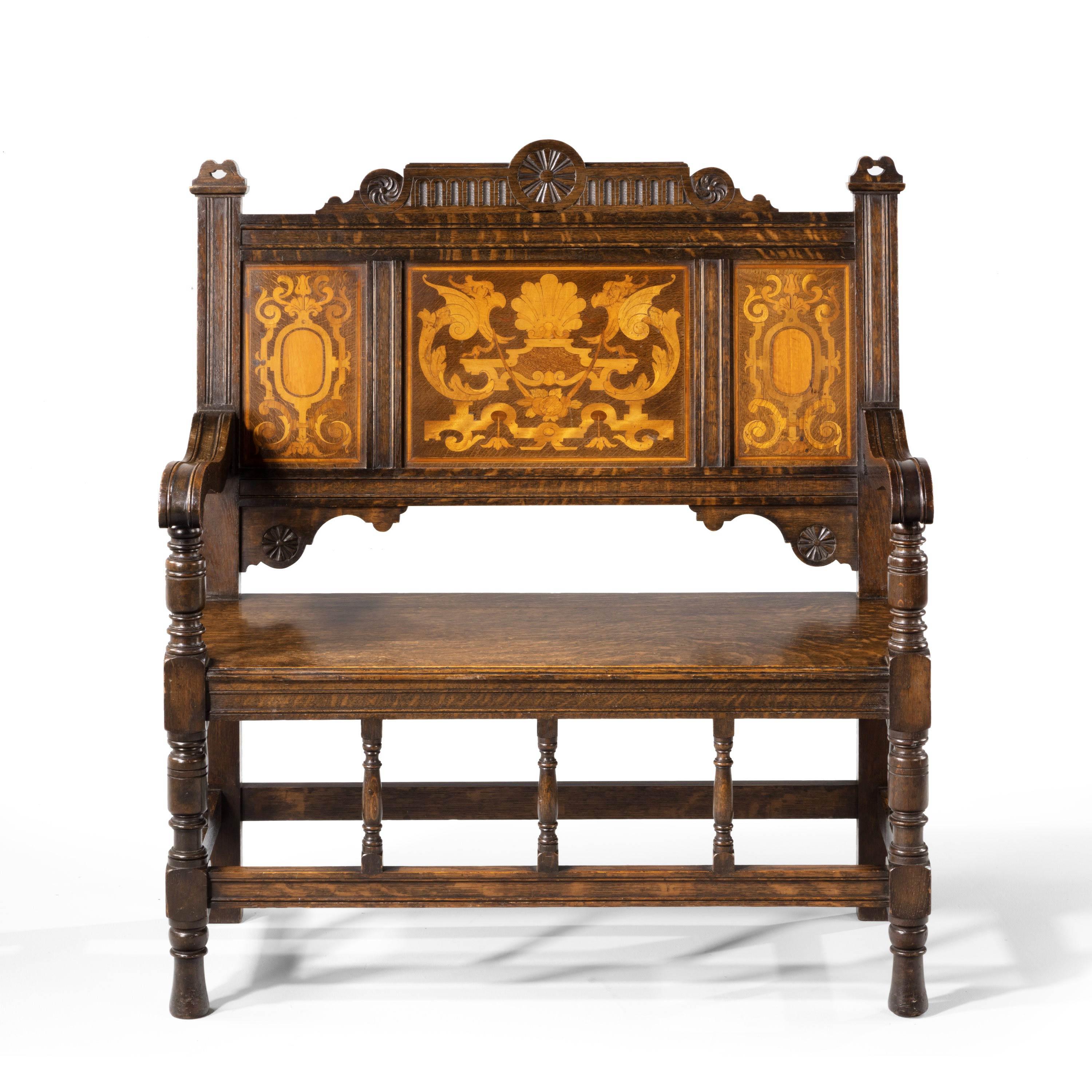 A most unusual and very good quality oak hall bench. With finely carved framework over moulded stretchers. The back beautifully inlaid with marquetry panels and the top with a carved pediment. Excellent overall condition and of most unusual