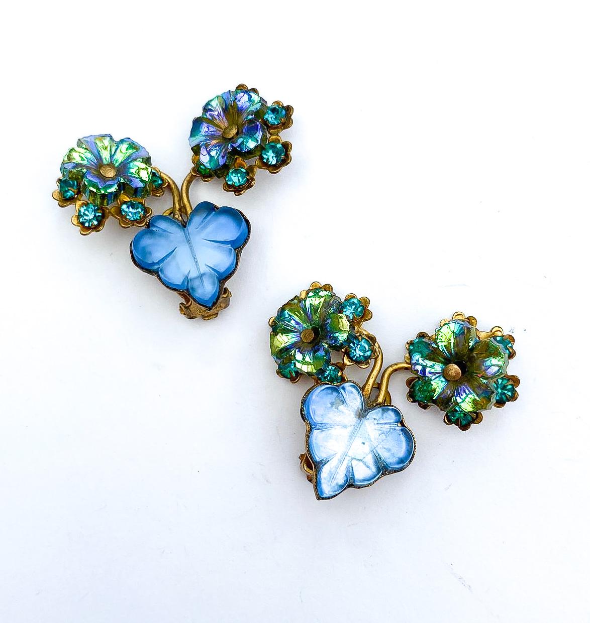 A very distinctive and most individual design, these beautiful eye catching earrings are bright and joyful. Set in gilded metal, a blue cast glass leaf sits at the centre, with two 'stems' set with dark aqua blue stones, and topped with a moving