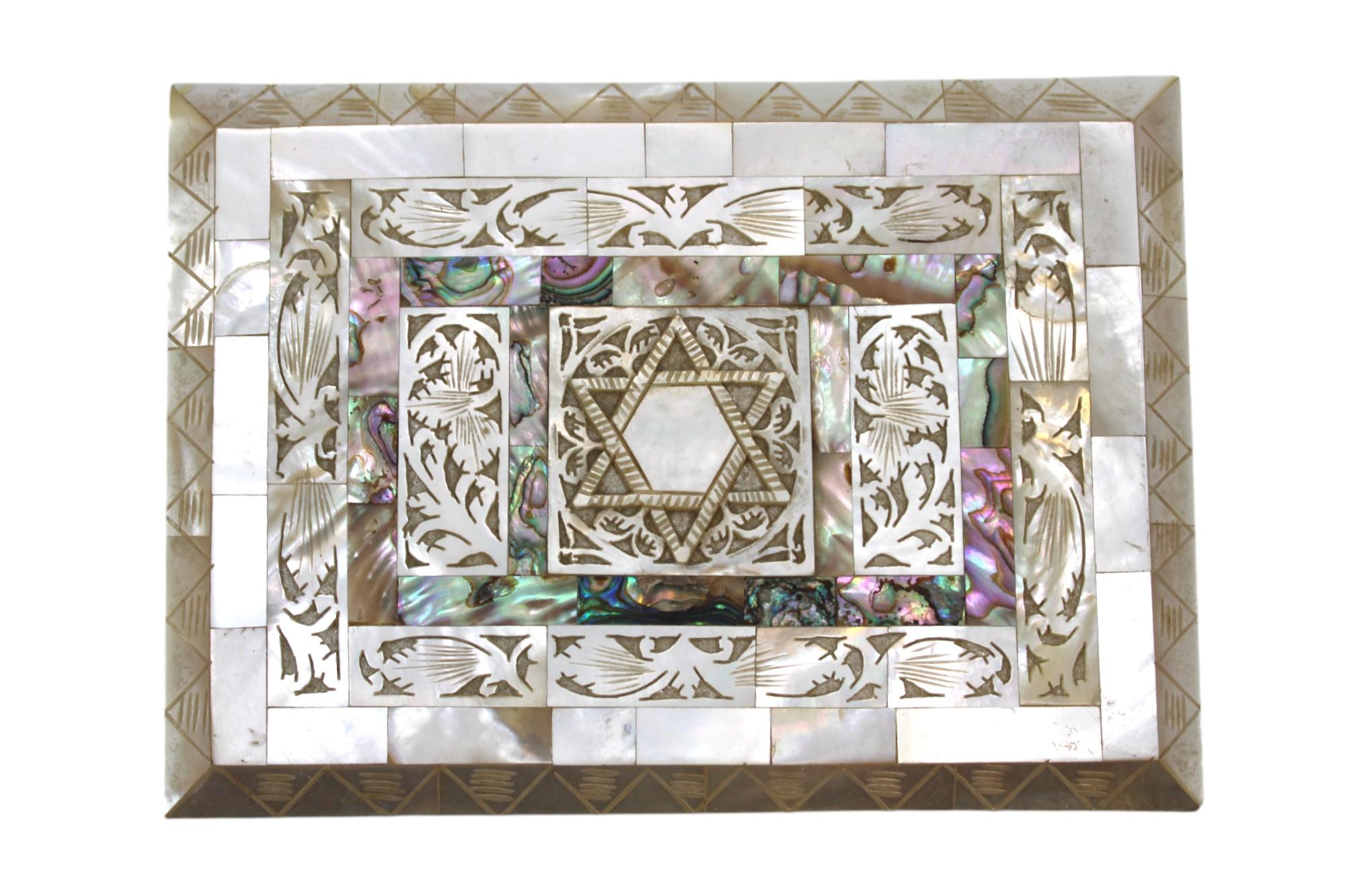 Dieses prächtige rechteckige Judaica-Schmuckkästchen ist ein wahres Fest traditioneller Handwerkskunst und raffinierter Kunstfertigkeit. Es ist vollständig mit glänzenden Perlmuttkacheln furniert, die in einem kachelartigen Mosaikmuster angeordnet
