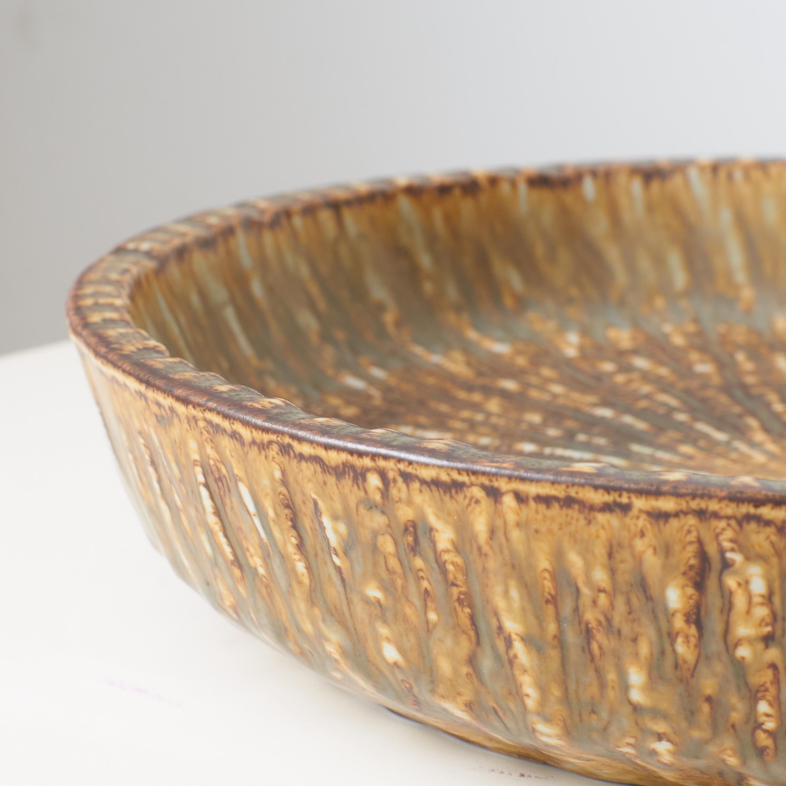 Ceramic A mottled brown and yellow deep sided round shaped dish by Gunnar Nylund For Sale