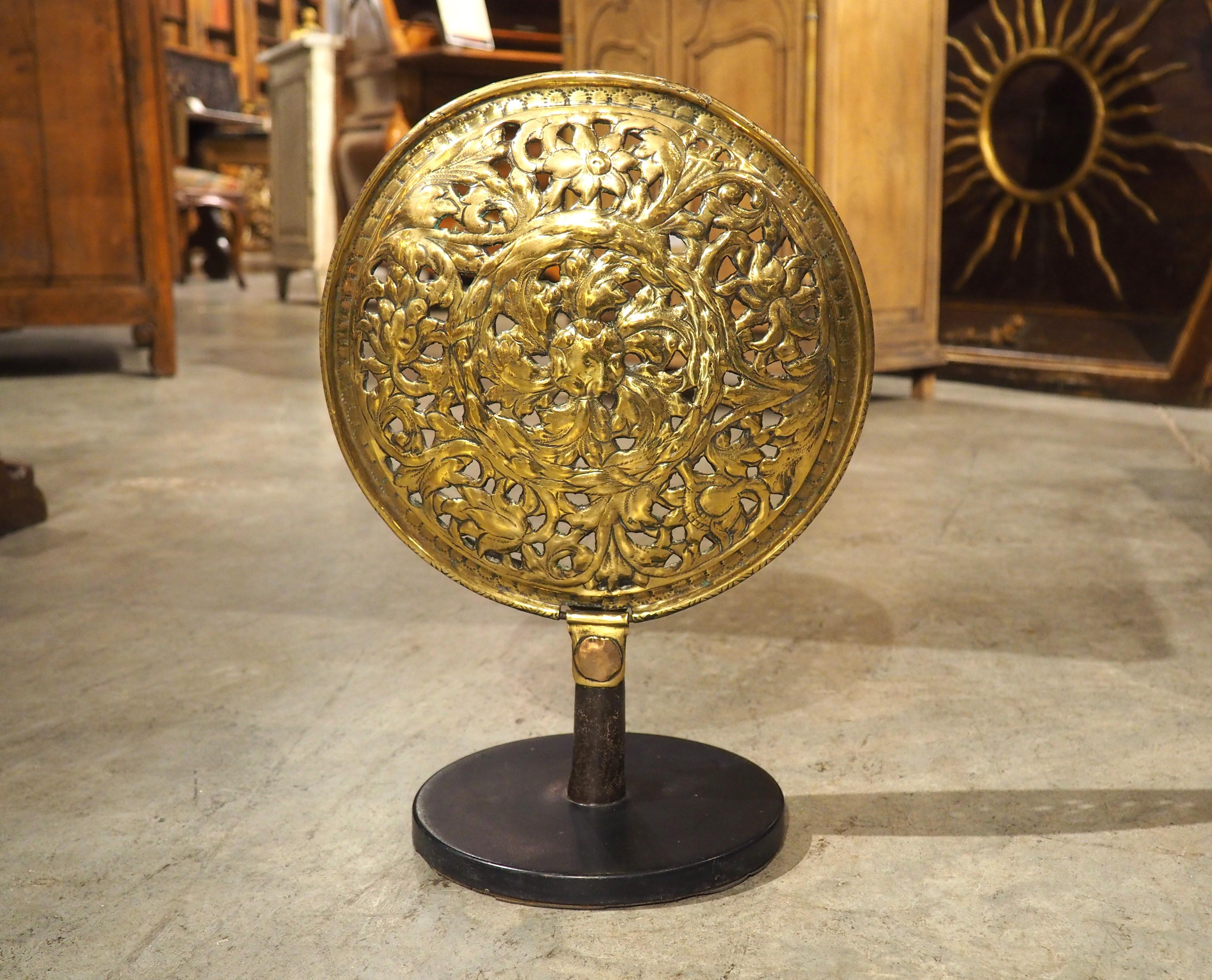 Dieses stark durchbrochene Zierelement aus Messing aus Frankreich war ursprünglich der Deckel eines Bassinoire aus der Zeit um 1600. Ein Bassinoire ist ein Gerät, bei dem heiße Kohlen in ein belüftetes Gefäß eingeführt werden, das unter die Laken