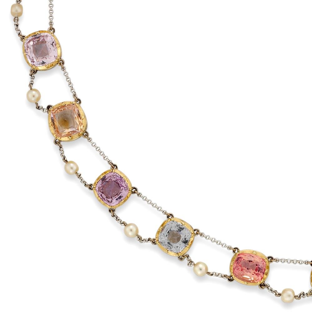 A multi colour sapphire necklace, the twenty four assorted cushion-cut, pastel coloured sapphires, weighing 47.1cts cut-down set in yellow to white gold collets separated by white gold chain suspensions with seed pearl set swags, to a cushion shaped
