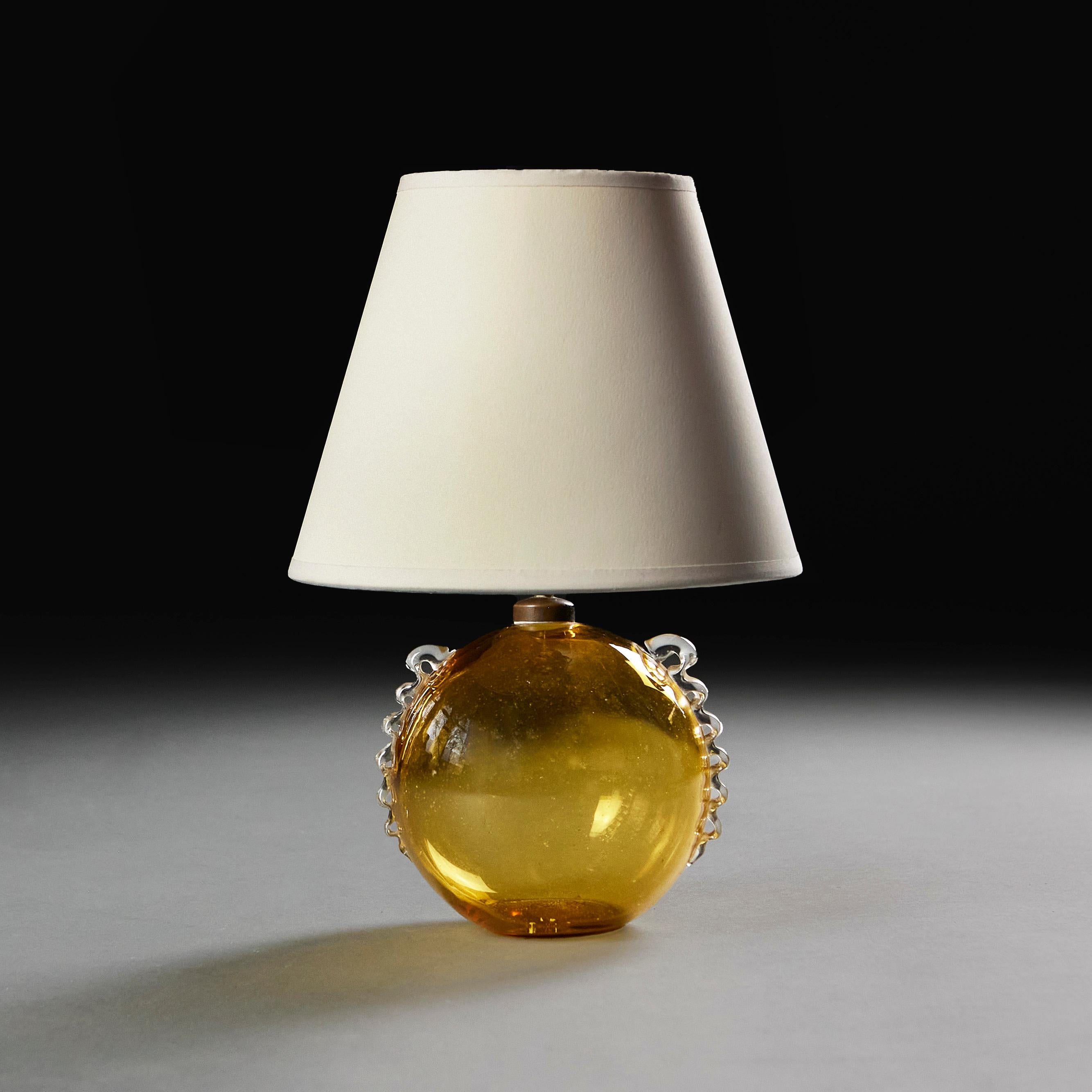 Italy, circa 1940
A mid twentieth century amber Murano glass bubble lamp, with serpentine clear glass handles applied to each side. 

Height  15.00cm
Height with shade  32.00cm
Diameter 15.00cm

Please note: Does not include the lampshade. Lamp has