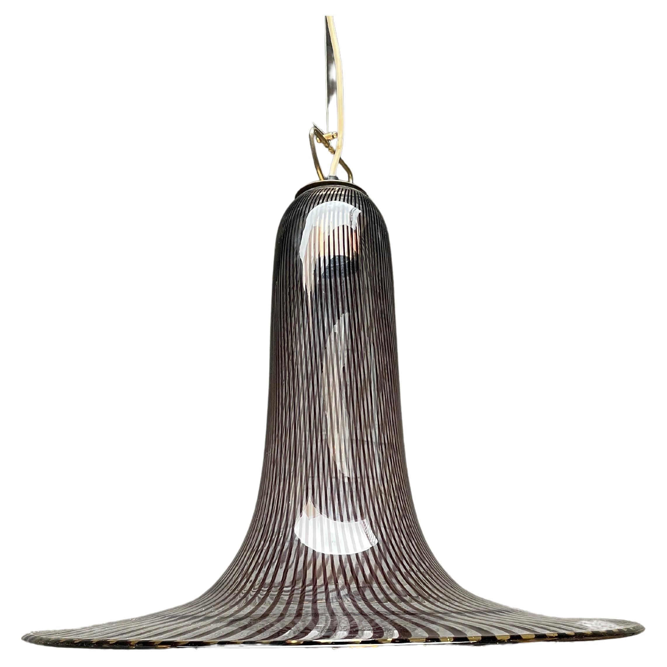 A large trumpet shaped Murano pendant in clear and purple striped crystal with brass accents. The drop can be altered by the wire stem. Designed by Lino Tagliapietra for Venini.

Can be re wired for any countries code