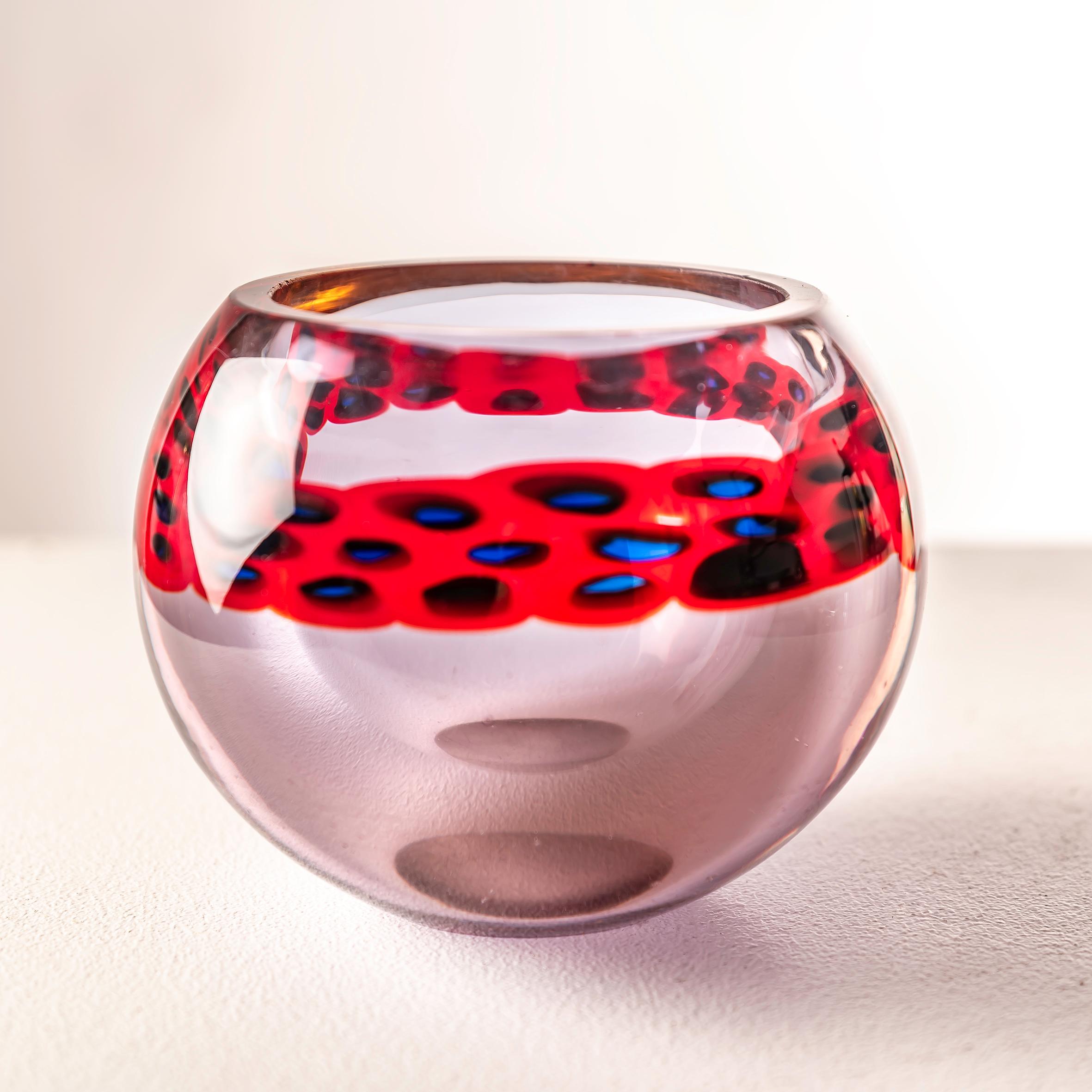 El jarrón de cristal Murrine de Antonio da Ros para Cenedese, Italia, hacia la década de 1960, entrelaza vibrantes tonos rojos y tranquilizantes azules en una danza de maestría vidriera. La delicadeza de Da Ros amplifica el encanto de la técnica