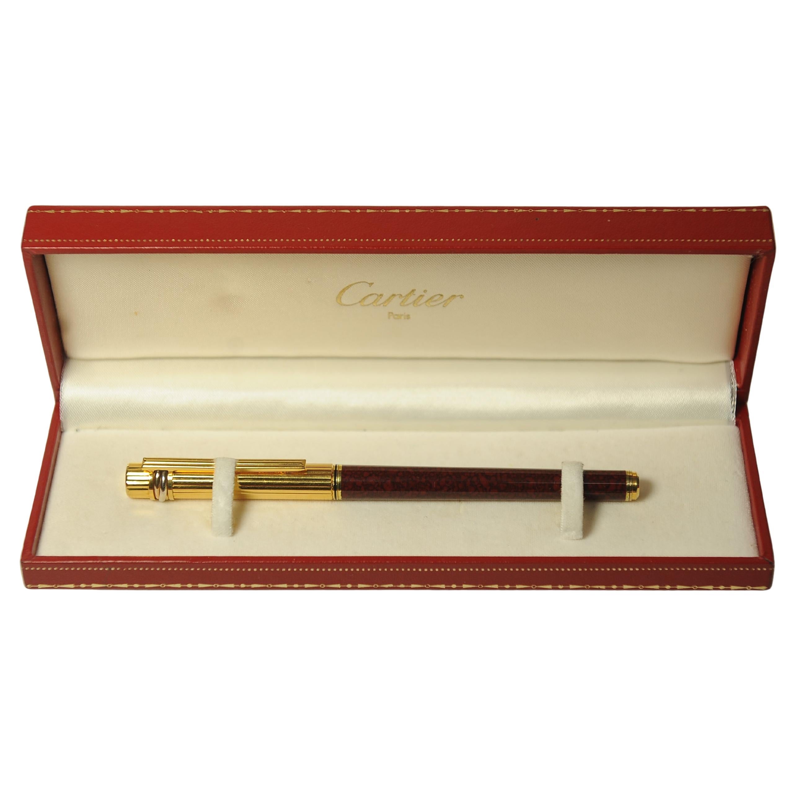 Elegant Cartier Burgundy Lacquer & 18 Carat Gold Plate Trinity Rollerball Writing Pen With Cartier Case.

Cartier pens are designed by Cartier, & are manufactured by Montblanc. This collaboration allows Cartier to produce high-quality, luxury pens