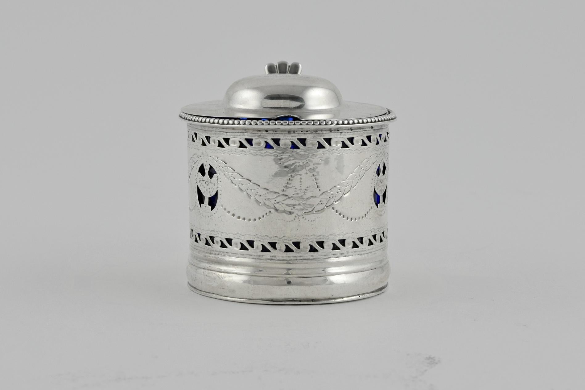 Dieser charmante kleine Senftopf wurde 1800 in Dublin hergestellt. Die Senfkanne ist mit gravierten Zacken und einem durchbrochenen Silberkorpus verziert, der das einzigartige blaue Glasinnere durchscheinen lässt. Auf dem gewölbten Deckel ist ein
