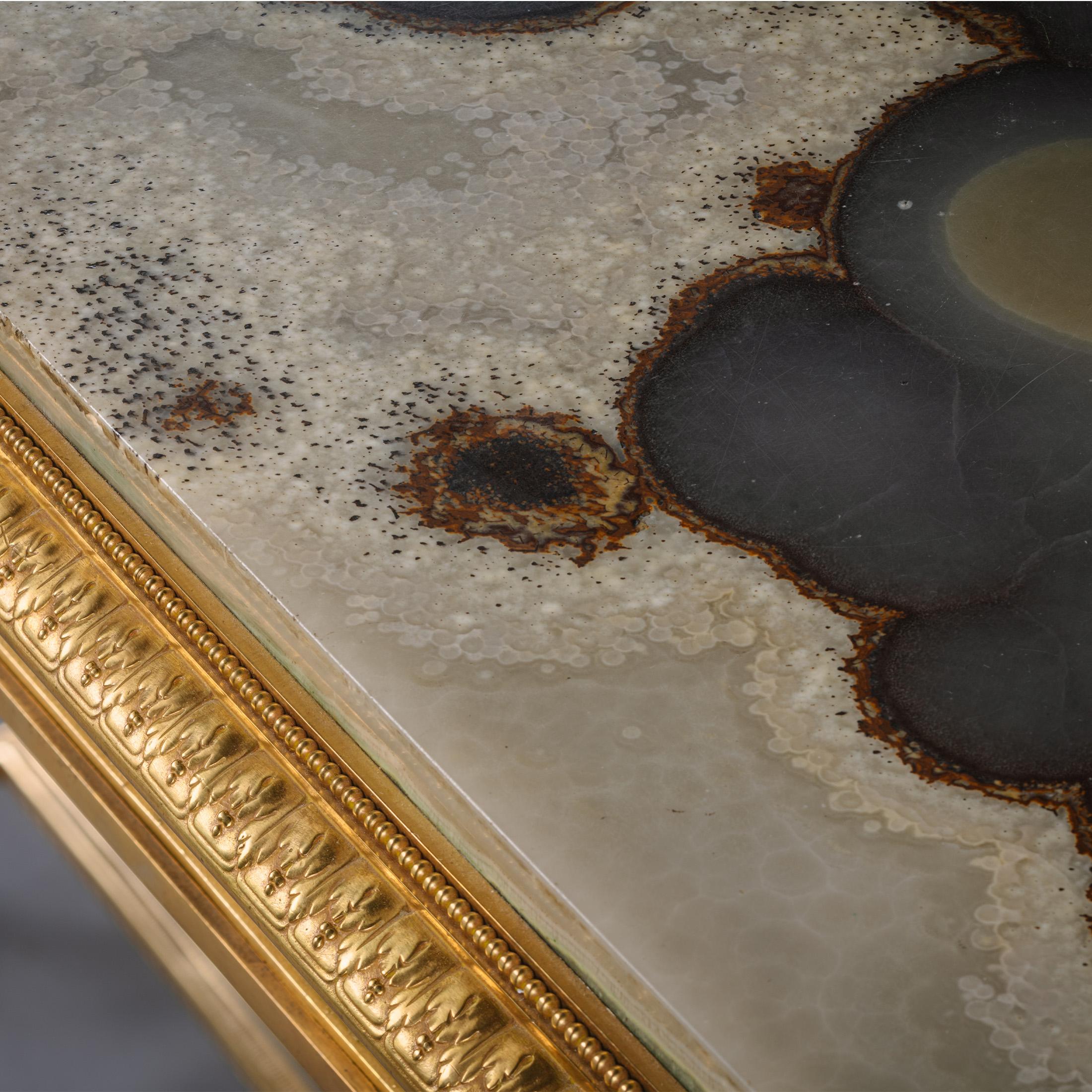 Table centrale Napoléon III en bronze doré et onyx, par la Maison Marnyhac, Paris. 

Signée sur le bord du châssis 'MAISON MARNYHAC 1. RUE DE LA PAIX PARIS'.

Cette table centrale opulente présente un plateau en onyx aux motifs magnifiques,
