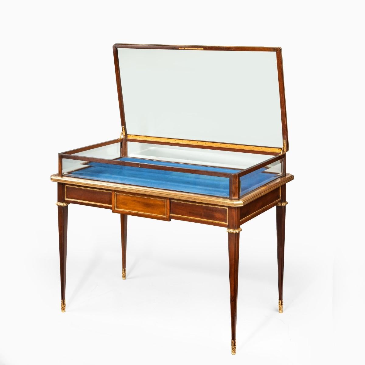  A Napoleon III freestanding mahogany bijouterie cabinet, of rectangular form with bevelled glass within an ormolu frame cast with reeded and palmette borders, the top with a safety hinge mechanism, all above a disguised frieze drawer set on slender