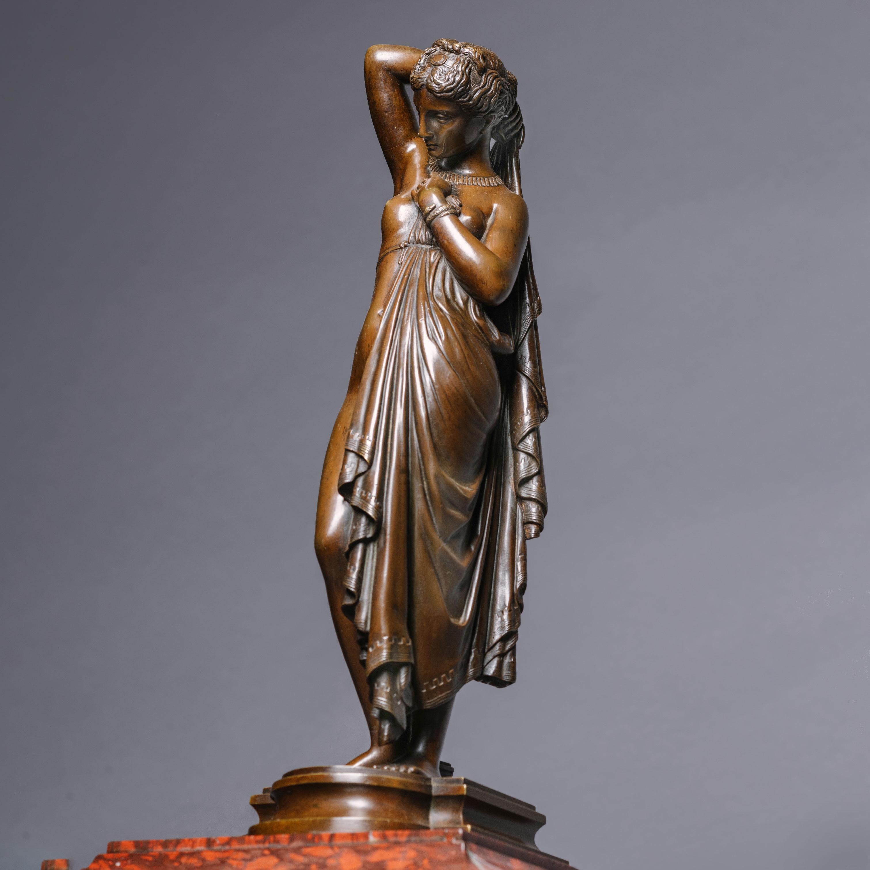 A Napoléon III Marble Mantle Clock With A Patinated Bronze Figure of 'Phryné' by James Pradier. France, Circa 1860.

Surmounted by a finely cast patinated bronze figure of the Grecian courtesan, 'Phryne', cast from the model by Jean Jacques (called