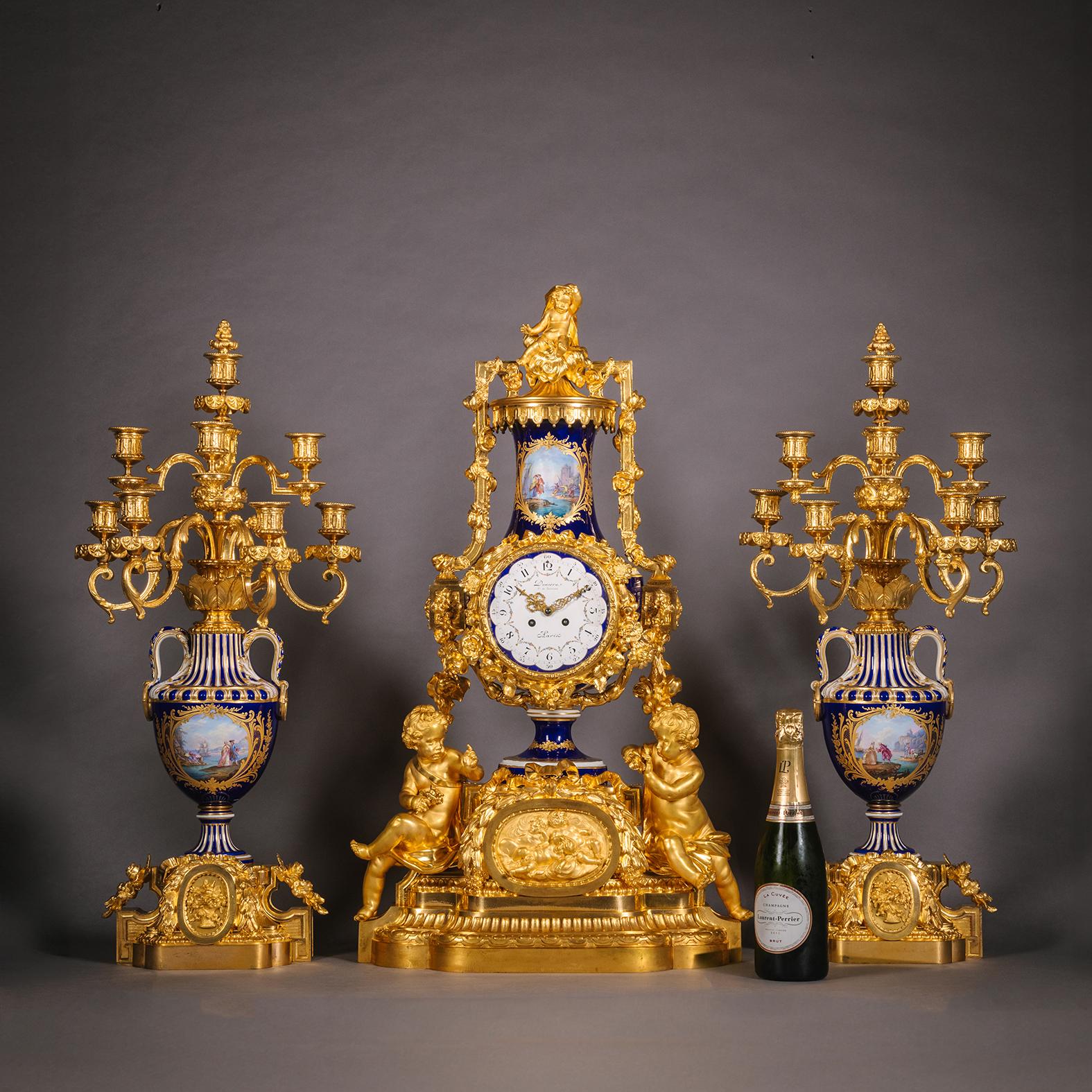 A Large and Exceptional Napoleon III Period Gilt-Bronze and Sèvres Style Porcelain Three-Piece Clock Garniture. By Denière, Paris. 

Comprising a mantle clock and pair of eight-light candelabra. The clock modelled as a vase atop a pedestal base with