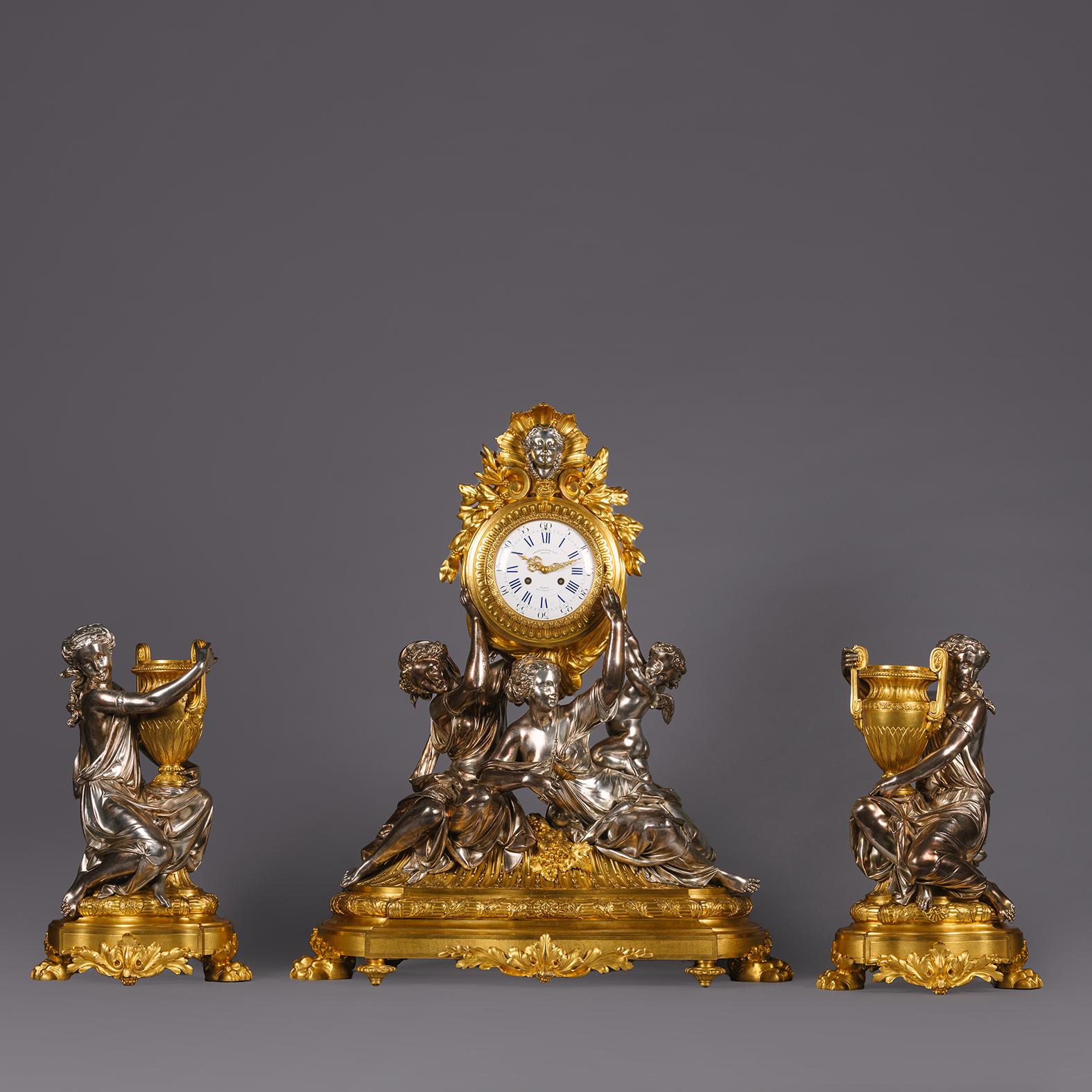 A Large and Important Napoléon III Gilt and Silvered-Bronze Sculptural Three-Piece Clock Garniture, By Charpentier, Paris.

Comprising a mantle clock and a pair of figural vases. The mantle clock modelled with two classically robed nymphs and a