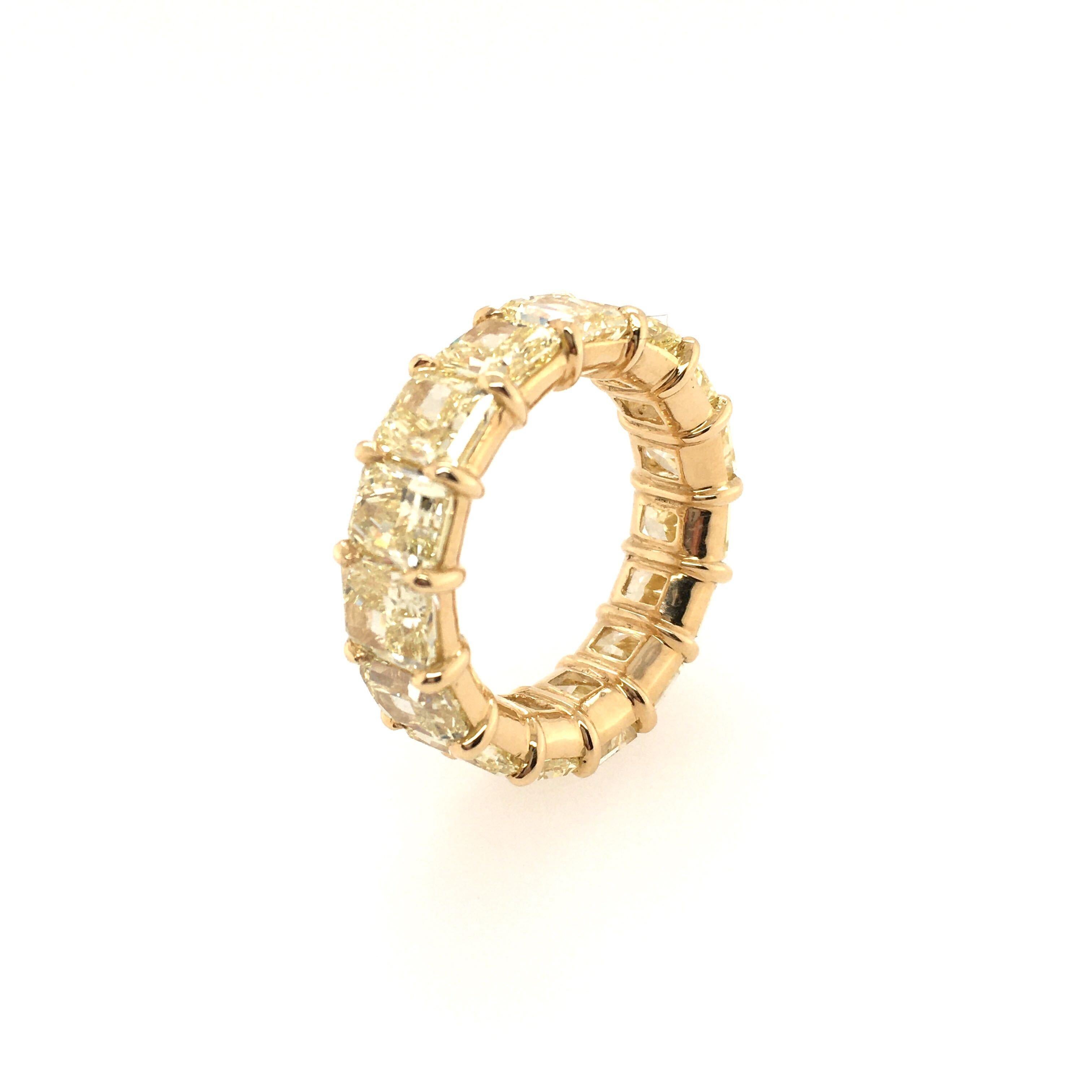 An 18 karat yellow gold and natural fancy yellow diamond eternity band. Of shared prong design, set with 15 cut-cornered rectangular modified brilliant cut natural fancy yellow diamonds, ranging in size from 0.66 to 0.89 carat. total diamond weight
