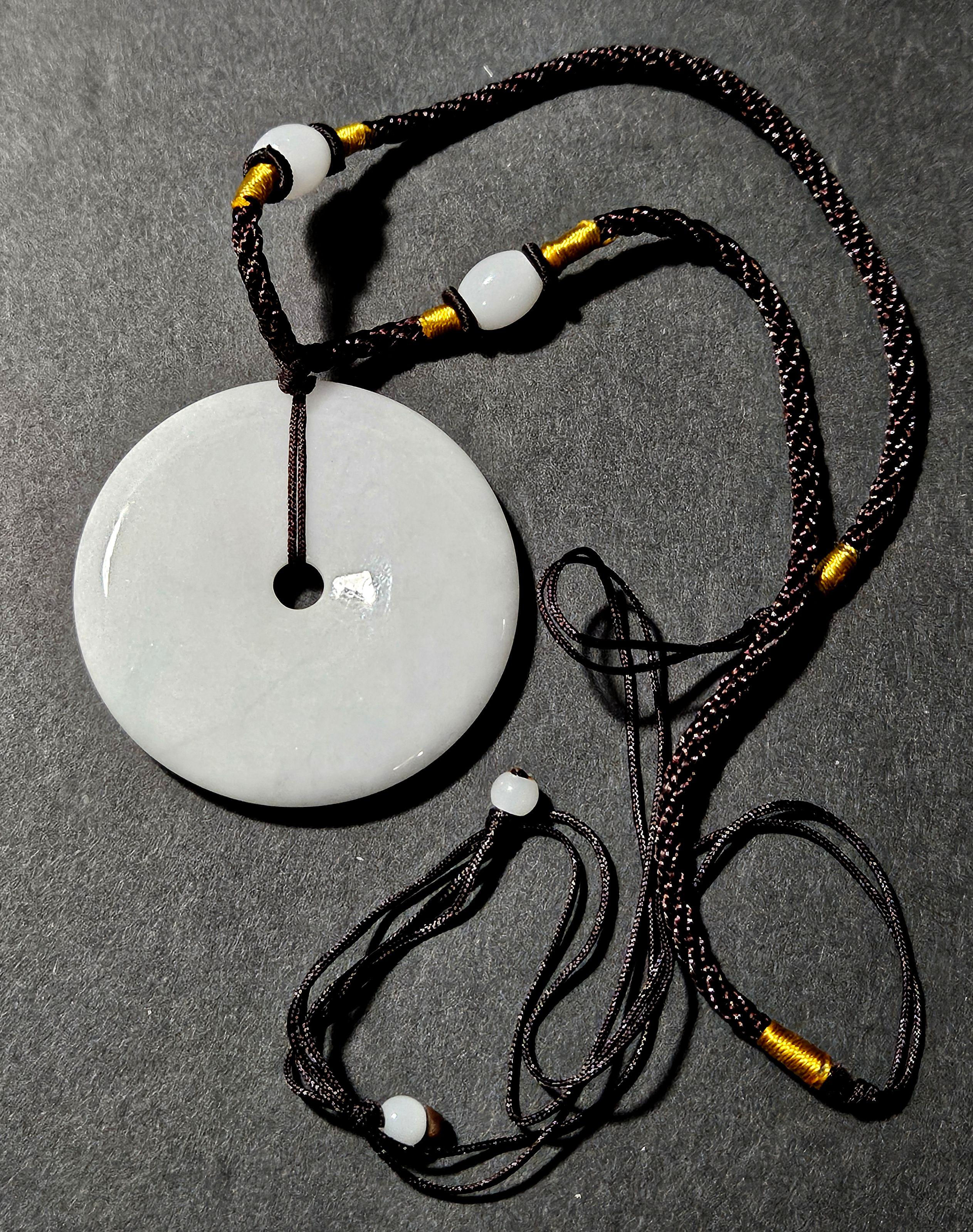 Pendentif disque en jadéite naturelle du Myanmar de couleur violet clair Ric#JD005 dans sa boîte en bois. Les couleurs semblent être le blanc et le violet clair. 