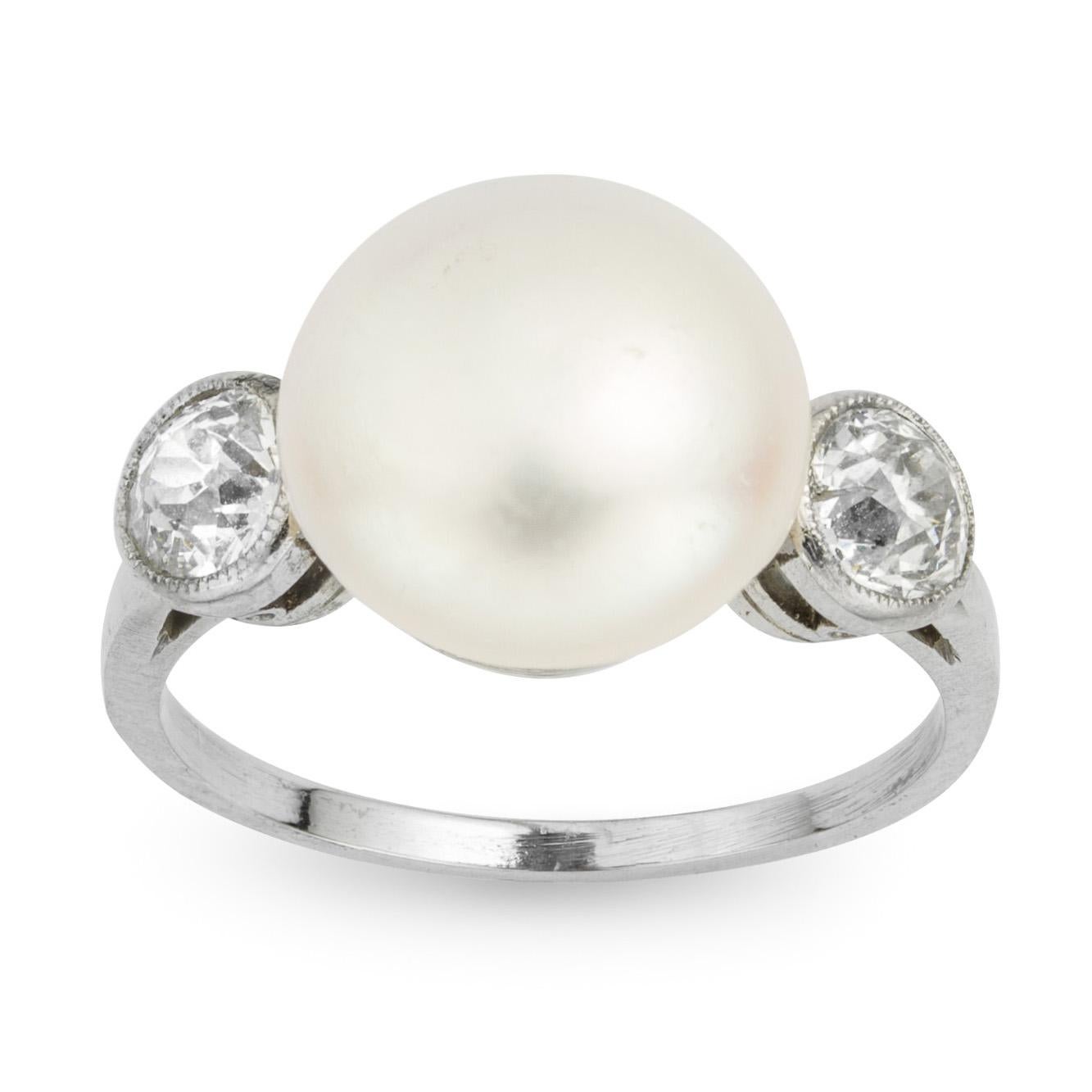 A natural pearl and diamond three stone ring, the bouton pearl measuring approximately 10.3mm in diameter, flanked by two old brilliant-cut diamonds, estimated to weigh a total of 0.5 carats, millegrain set to a platinum mount with chenier gallery