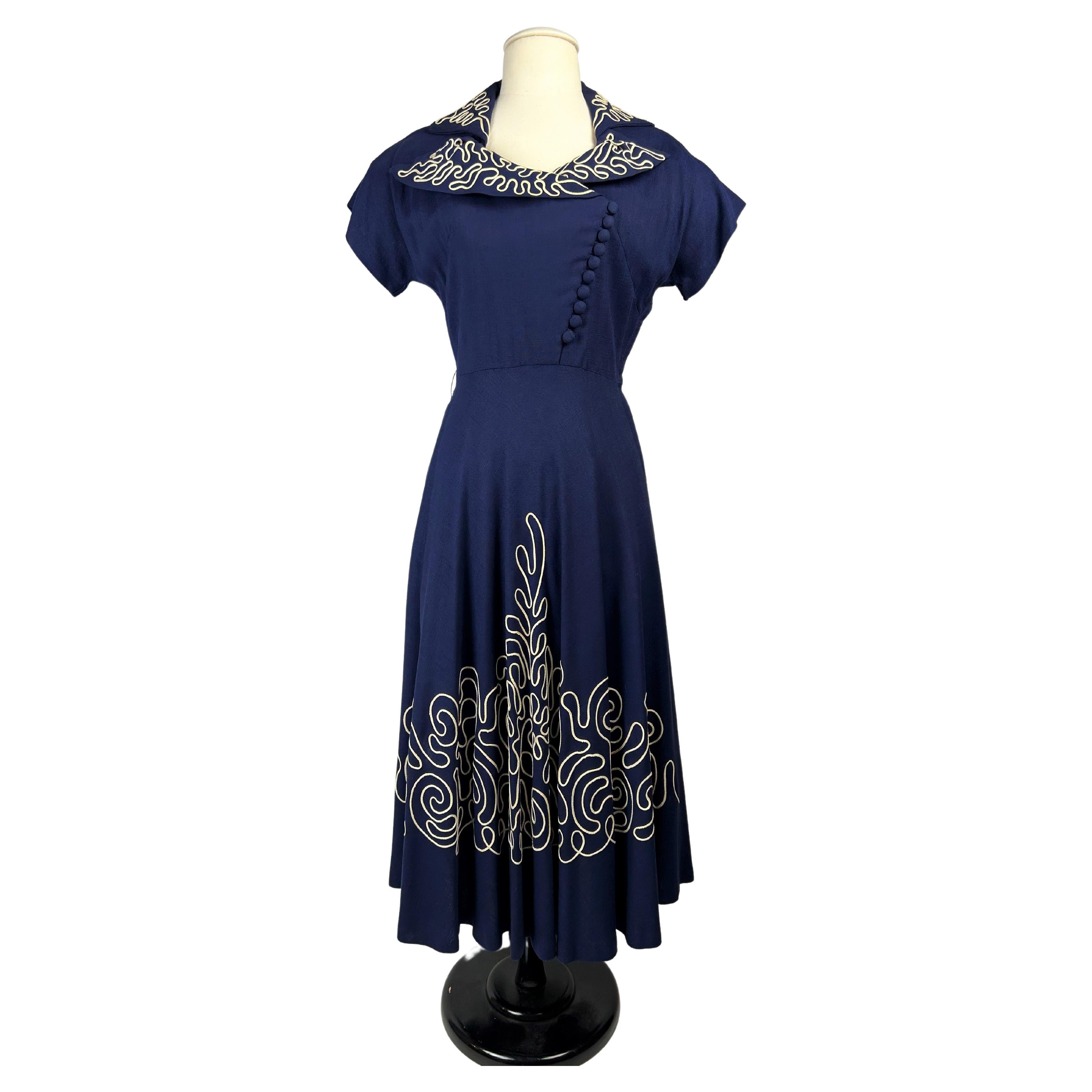 Circa 1945-1950
France
Marinière day dress in navy blue polyamide fabric inspired by the work of the Maison Henri à la Pensée and dating from the late 1940s. Bustier with asymmetrical buttoning, large collar with folded-over points and small raglan