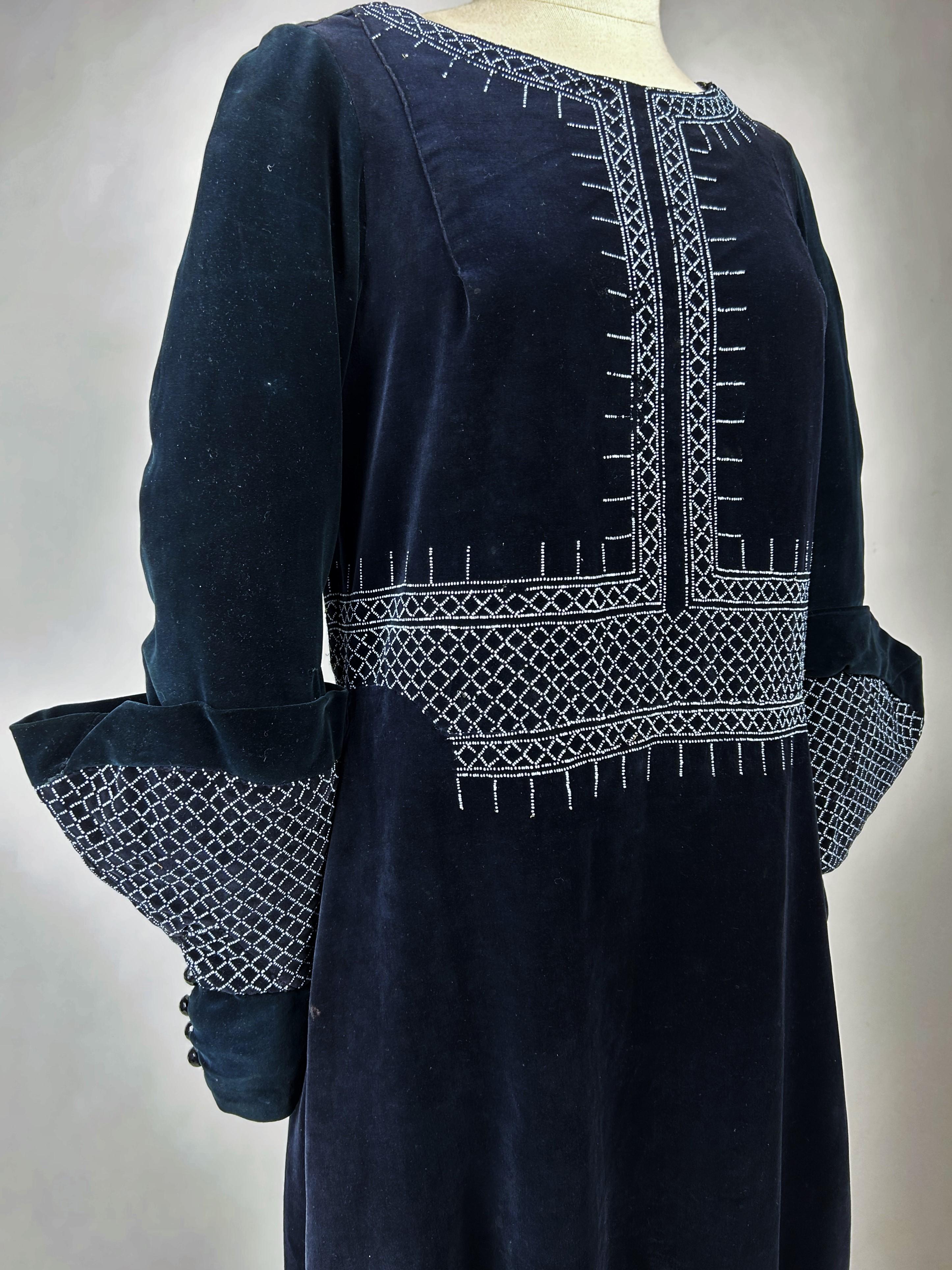 CIRCA 1925-1930

Frankreich

Nicht identifiziertes Couture-Tageskleid aus marineblauem Samt und weißem Glasperlensiebdruck aus der Zeit des Art déco. Ein Sac Kleid Schnitt, ovaler Ausschnitt und lange Ärmel mit Musketiermanschetten. Sehr raffinierte