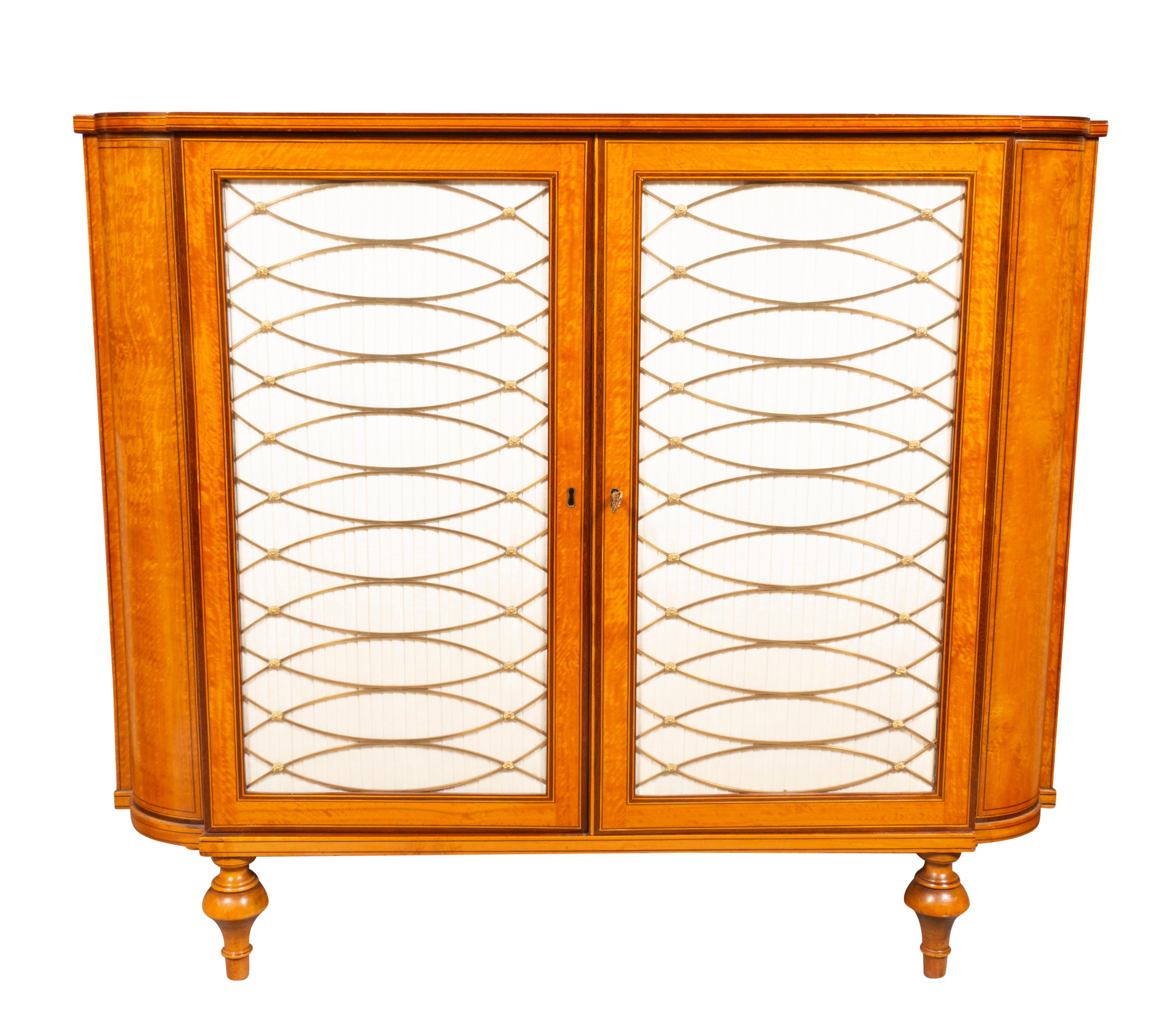 With a six inch variation in width. Each rectangular with rounded corners and cross banded top edge border over a conforming case with a pair banded silk lined brass grill doors opening to an interior with a shelf. Raised on toupie feet. Provenance;