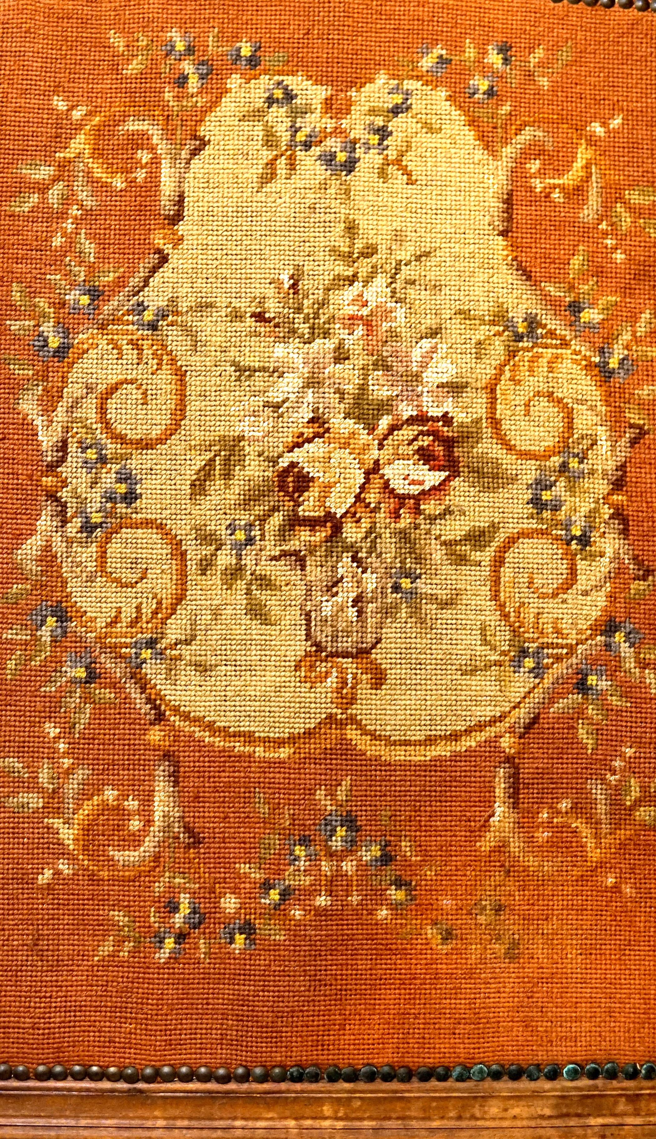Everything about this screen is charming, from the bunch of needlepoint flowers, to the ribbon-like wood carving that frames the screen. This is an antique English piece from the Victorian era, circa the third quarter of the 19th Century. The screen