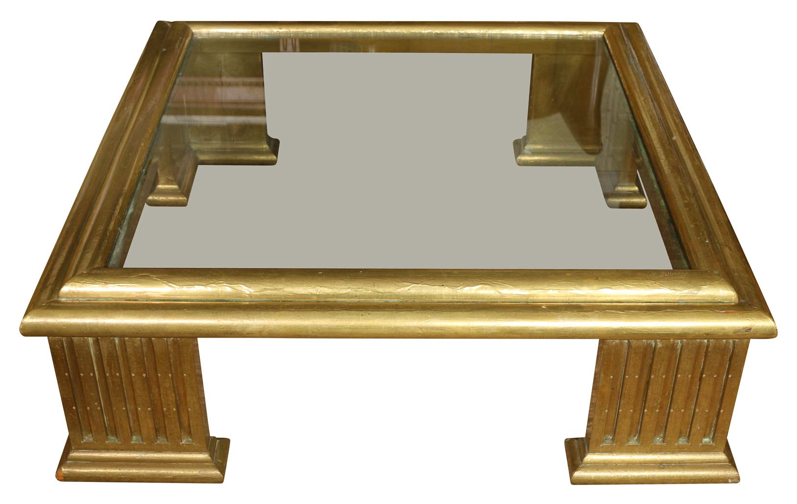 This striking table has star quality. Constructed of brass clad wood, the table features a brass clad over wood frame with an inset glass top. The L-shaped column feet add wonderful detail to this special piece.