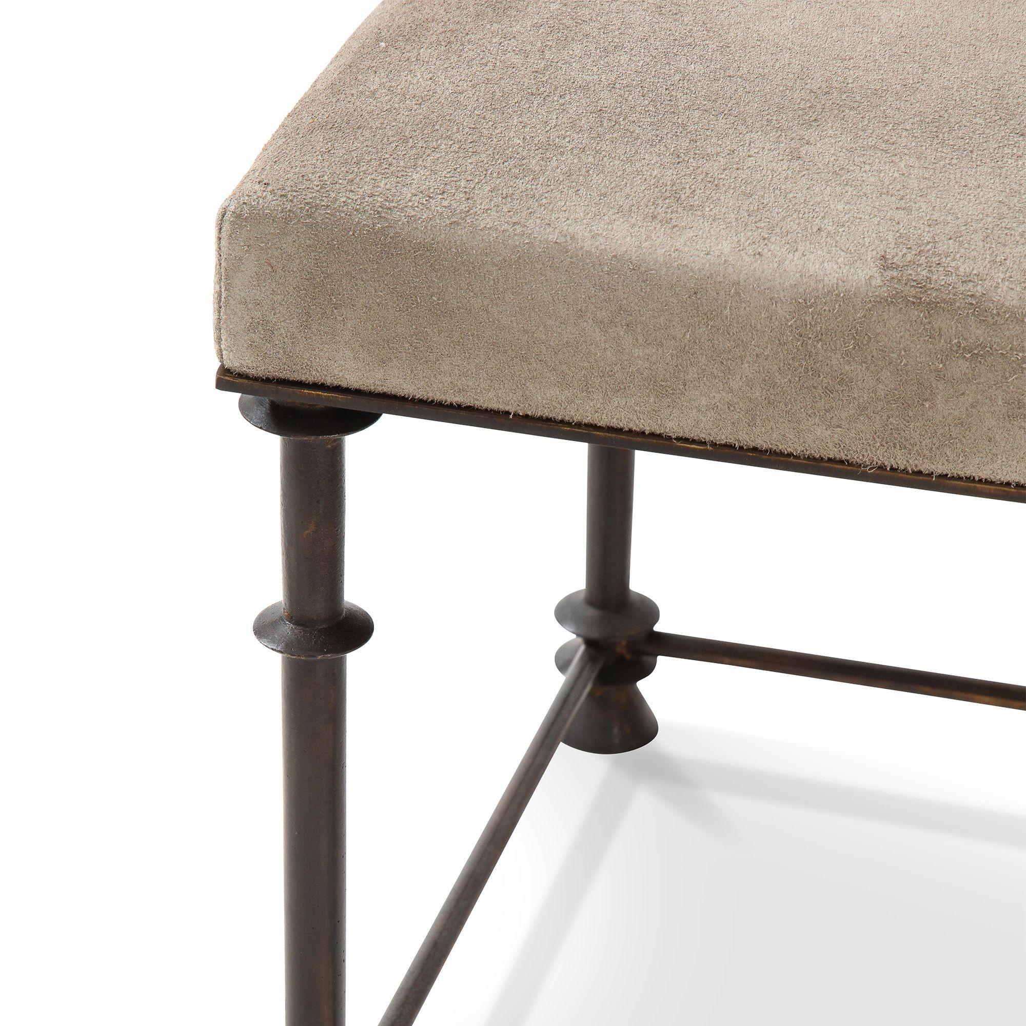 Un elegante taburete a medida con patas de bronce recubierto de 