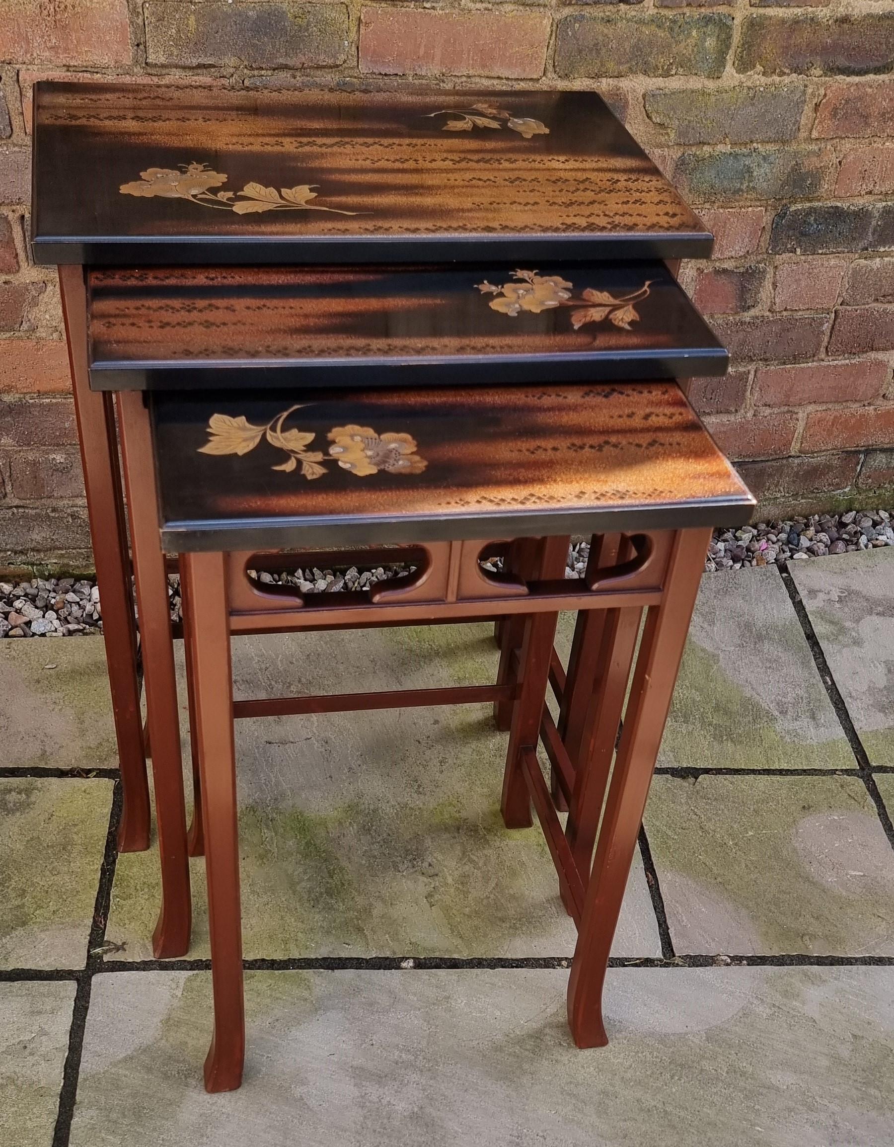 This distinctive and decorative nest of tables was made in Japan and dates to circa 1910. The simple legs and framework are finished in brown lacquer and consist of square legs with turned outfeet connected with plain stretchers both at the top and