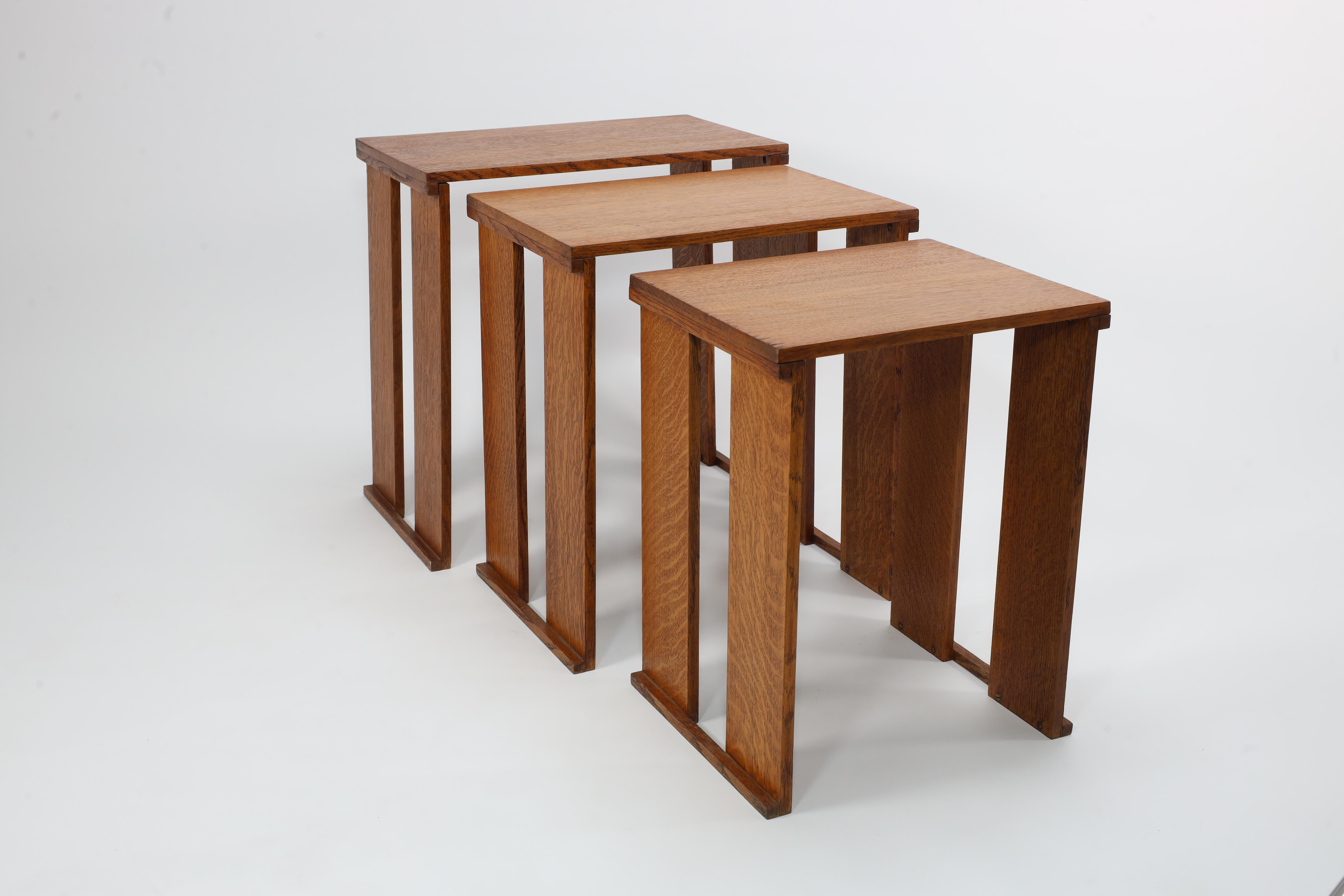 English A nest of three Art Deco wild grain oak side tables of planked construction.