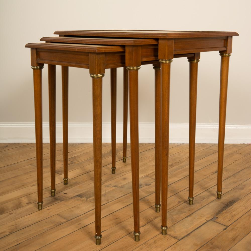 A nest of three mahogany tables attributed to Comte Circa 1940. Neoclassical design with fluted legs and parchment tops.
 Medium: 16