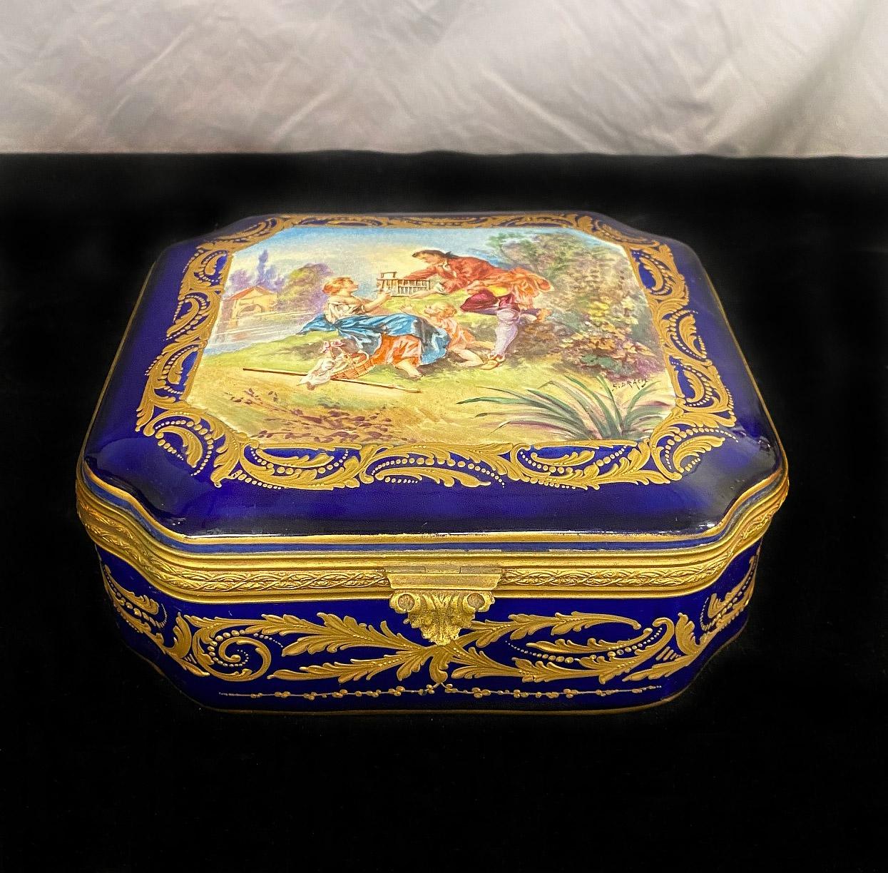 A nice late 19th century Sèvres style porcelain jewelry box and cover

Of rectangular shape, the top painted in the manner of Boucher with a couple of their child, within a raised gilt border, the sides similarly decorated with raised gilt scroll