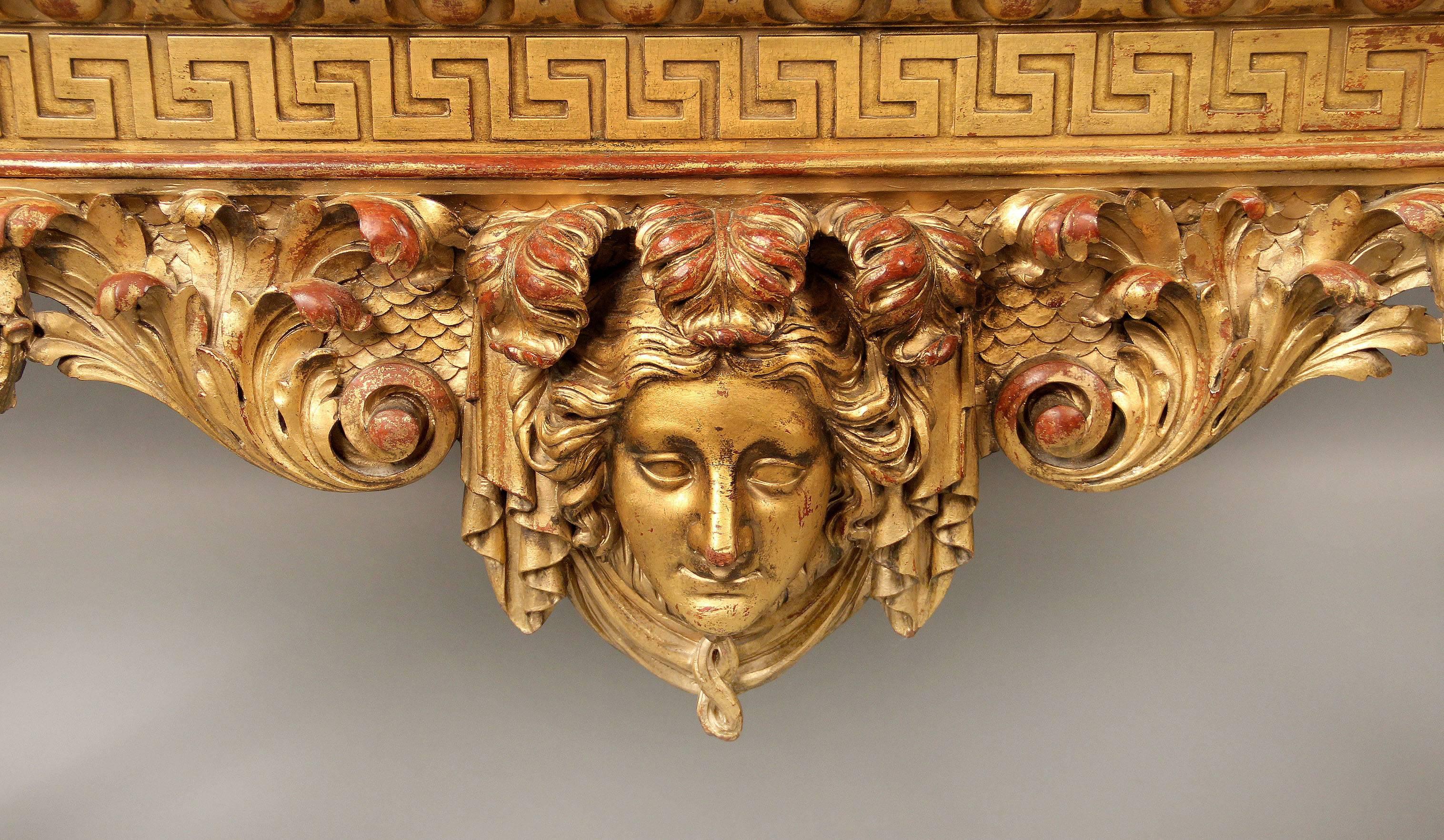 A nicely carved late 19th century giltwood English console.

A green marble top above a carved frieze, the designed console centred with a female mask with curtains and laurel swags, the legs with fierce lion faces and sitting on hairy paw feet.