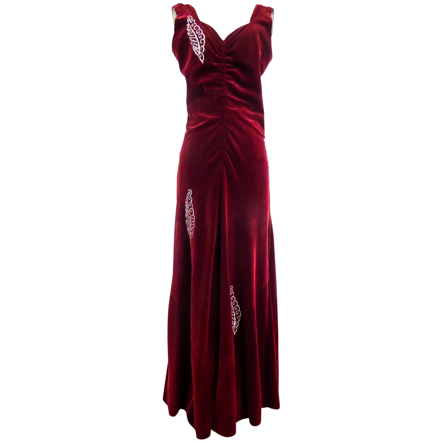 Circa 1935
France

Rare long collector's evening dress, French Haute Couture by Nicole Groult, famous sister of Paul Poiret and dating from the 1935s. Sleeveless dress in carmine red silk velvet underlined with Swarovski rhinestone embroidery with