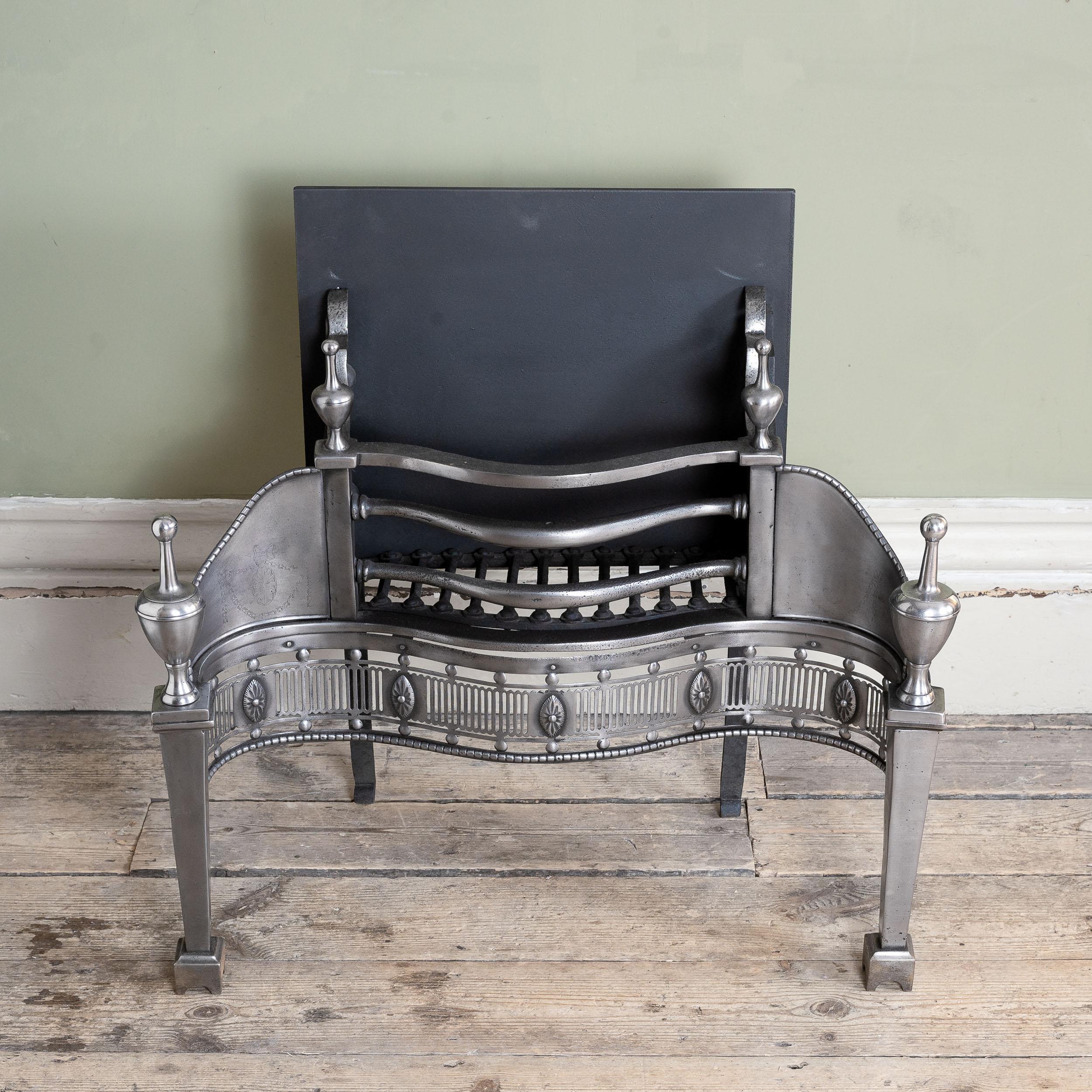 A Nineteenth century engraved steel and iron fire grate in the George III Neo-Classical style, with pierced serpentine fret and bold urn finials.

Dimensions:	73.5cm (29