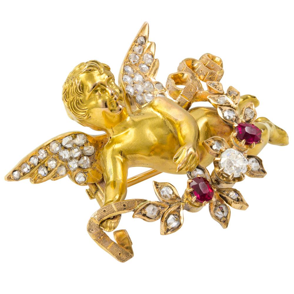 Broche chérubin en or français du XIXe siècle, le corps en or jaune avec des ailes incrustées de diamants taillés en rose, portant une guirlande de rubis ovales à facettes et de diamants taillés à l'ancienne, avec des extrémités de ruban torsadé,