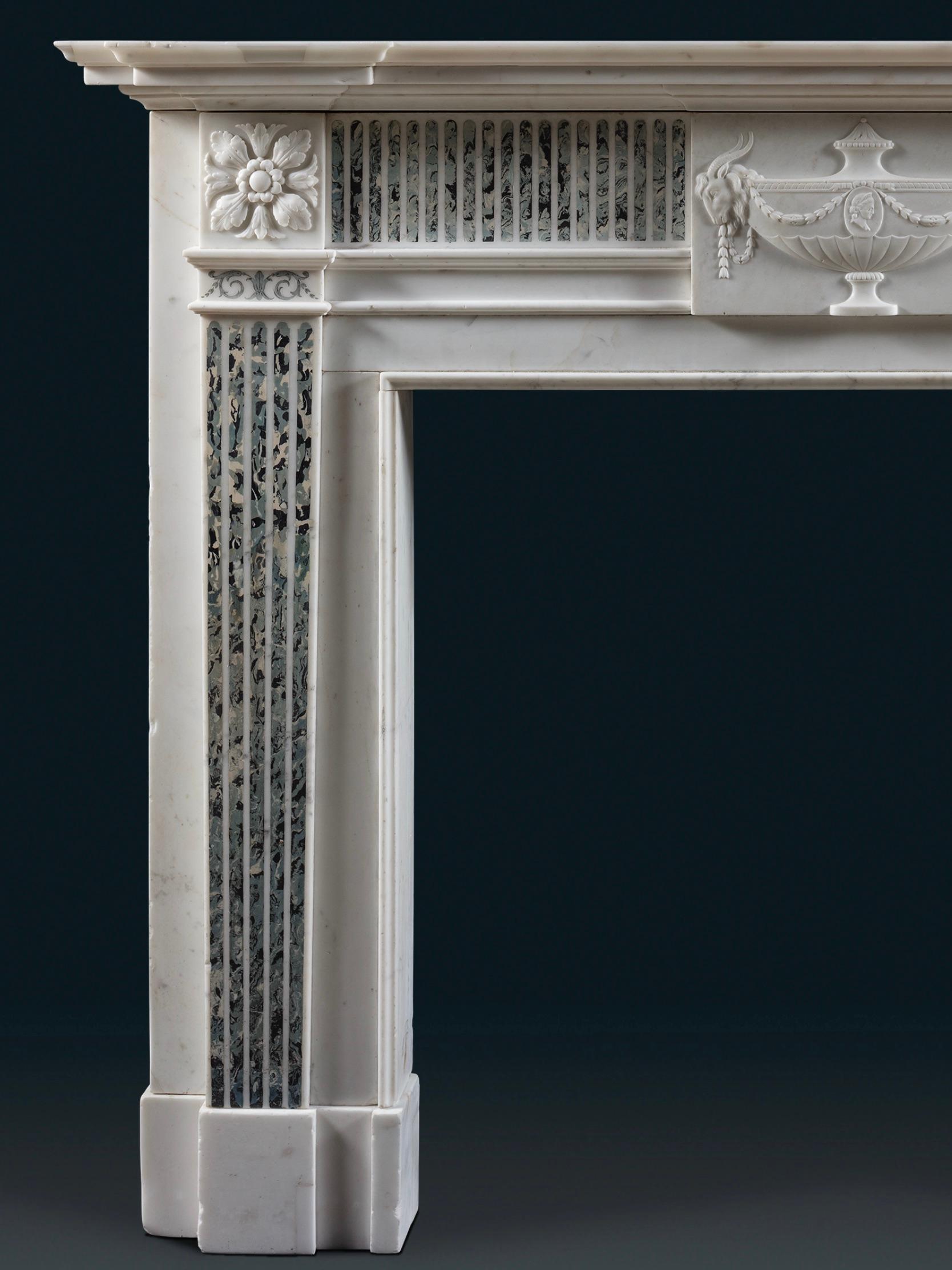 The breakfront moulded shelf is supported by a frieze with fluted scagliola details, resembling a light blue marble inlay. The same fluted detail is repeated on the jambs, surmounted by cornerblocks carved with paterae. The tablet at the centre of