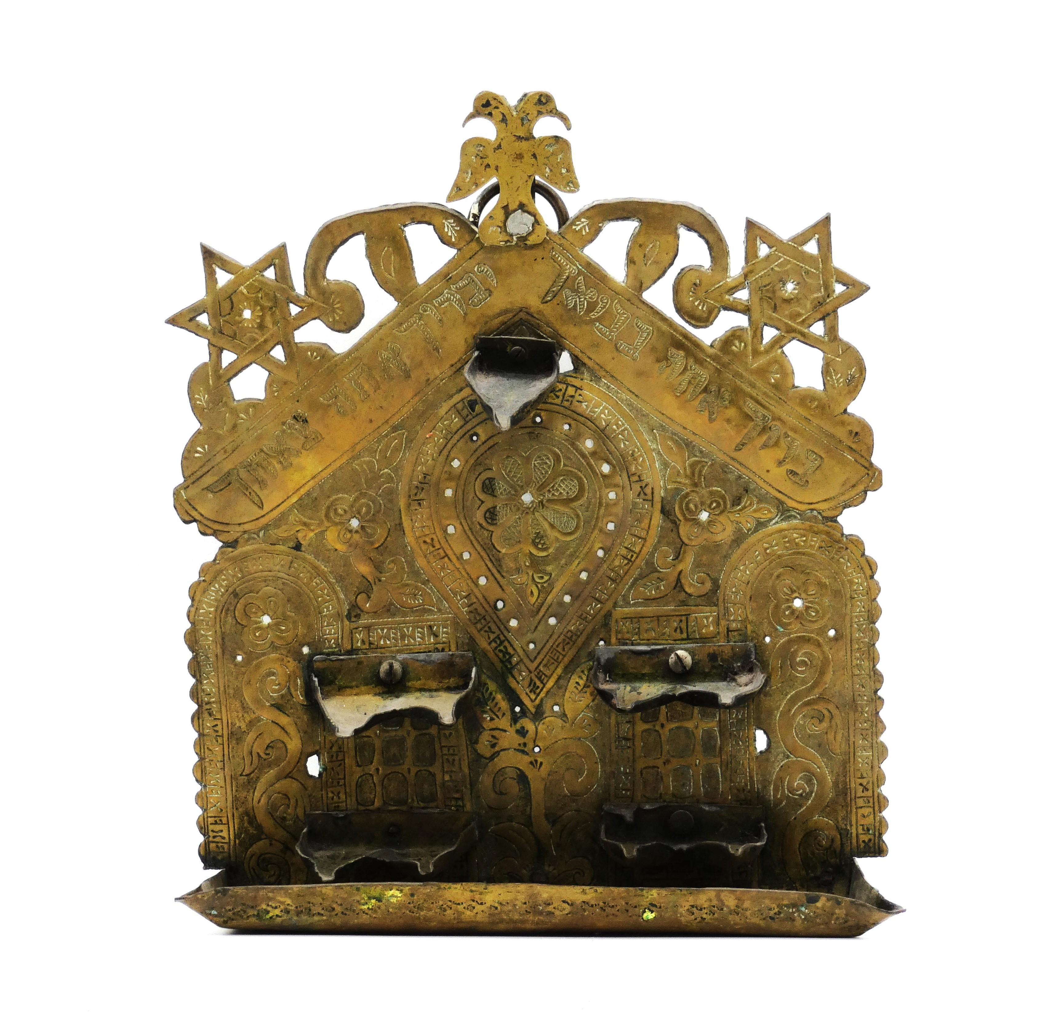 This  North African Hanukkah lamp has unique structural characteristics not seen in many Antique Hanukkah lamps.

Engraved on the backplate are many scrolling floral and foliate designs bordered by archways, windows, and teardrop motifs.

Surmounted