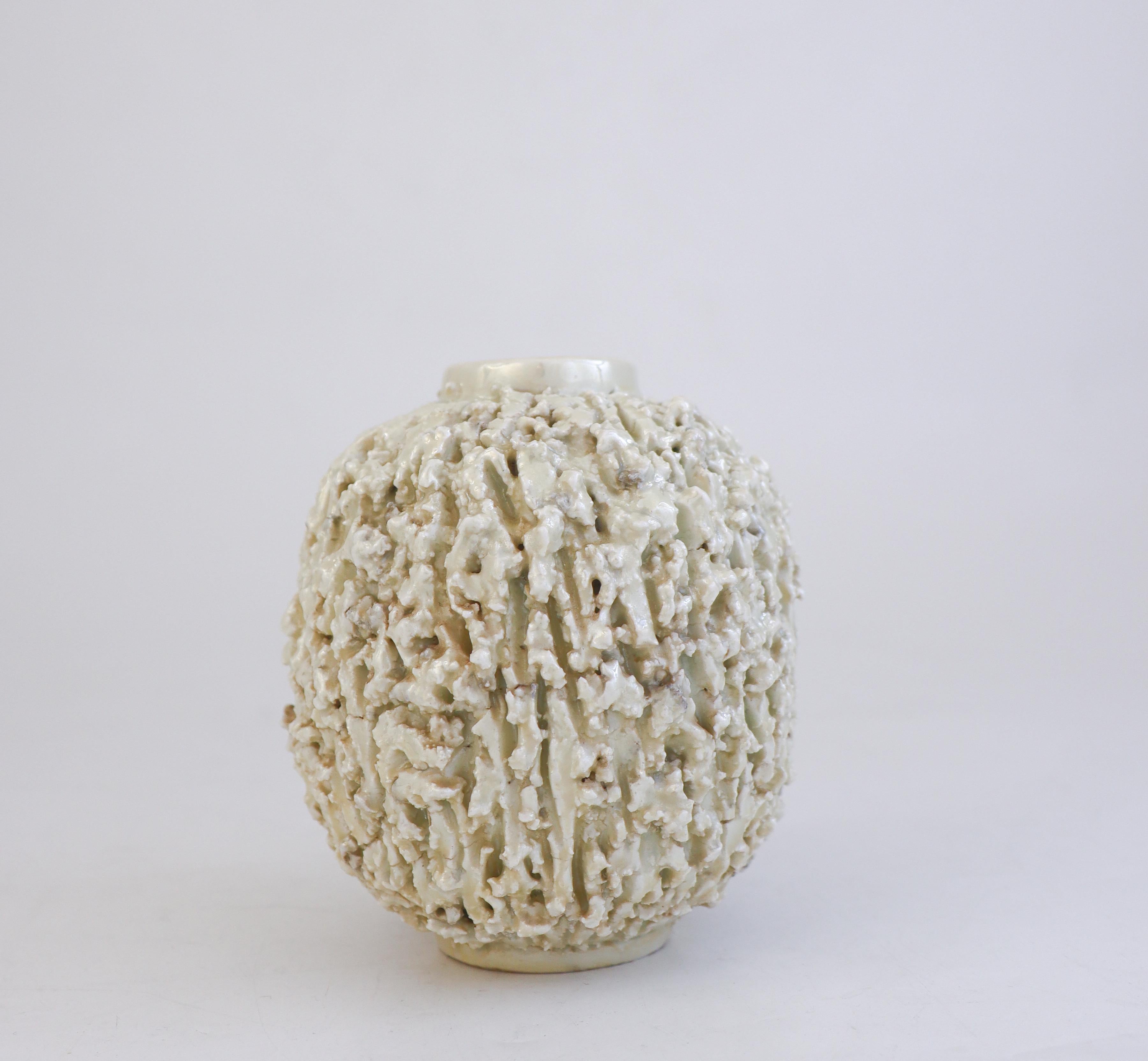 Un vaso riccio di colore bianco sporco disegnato da Gunnar Nylund a Rörstrand. È alto 11 cm (4,4