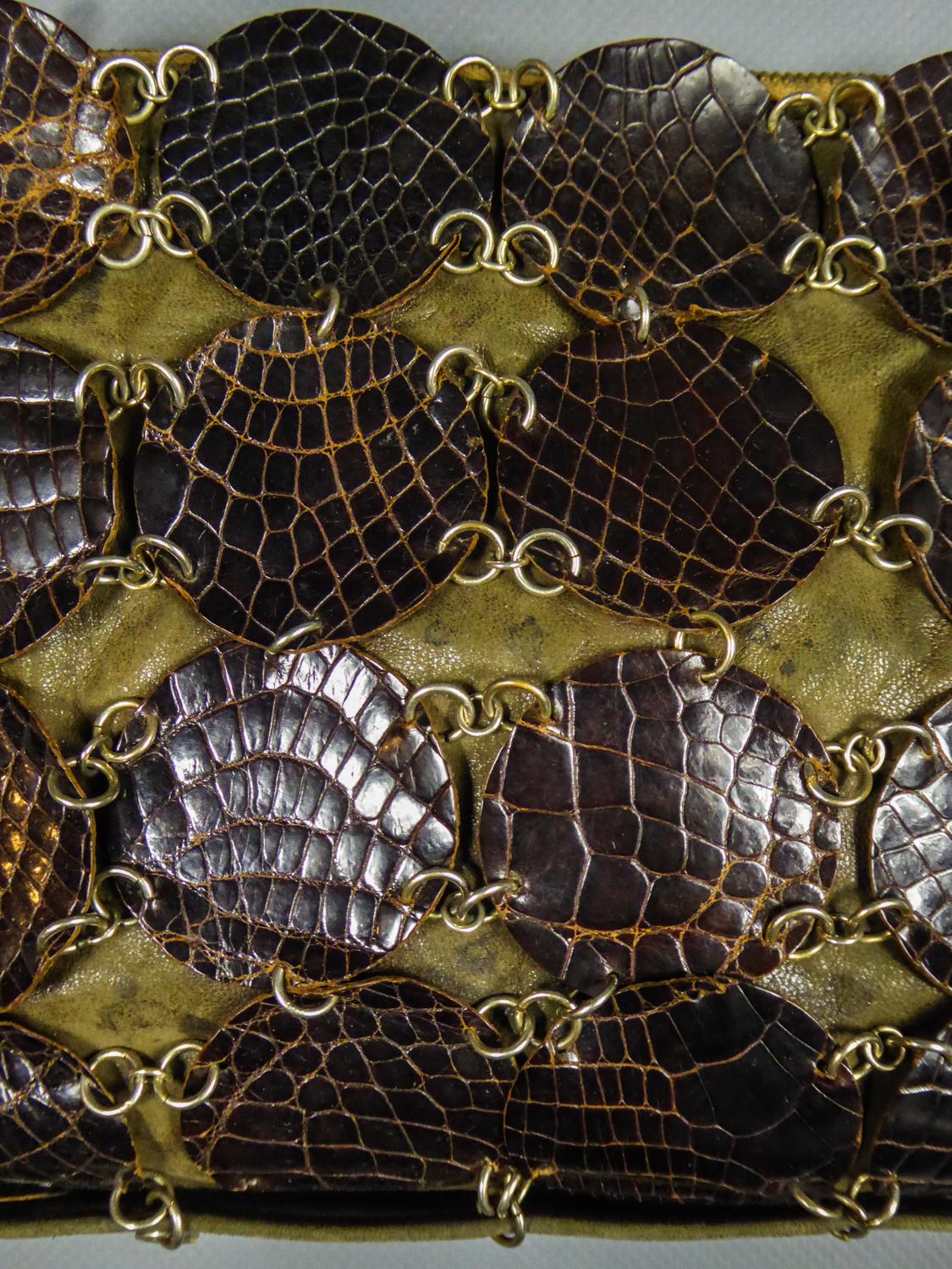 Circa 1968
France

Pochette de soirée ou petit sac à bandoulière en cuir kaki et plaquettes imitation crocodile de la célèbre Maison de Créateurs Paco Rabanne vers 1968. Fond en cuir de daim recouvert de larges pads en cuir de crocodile marron.