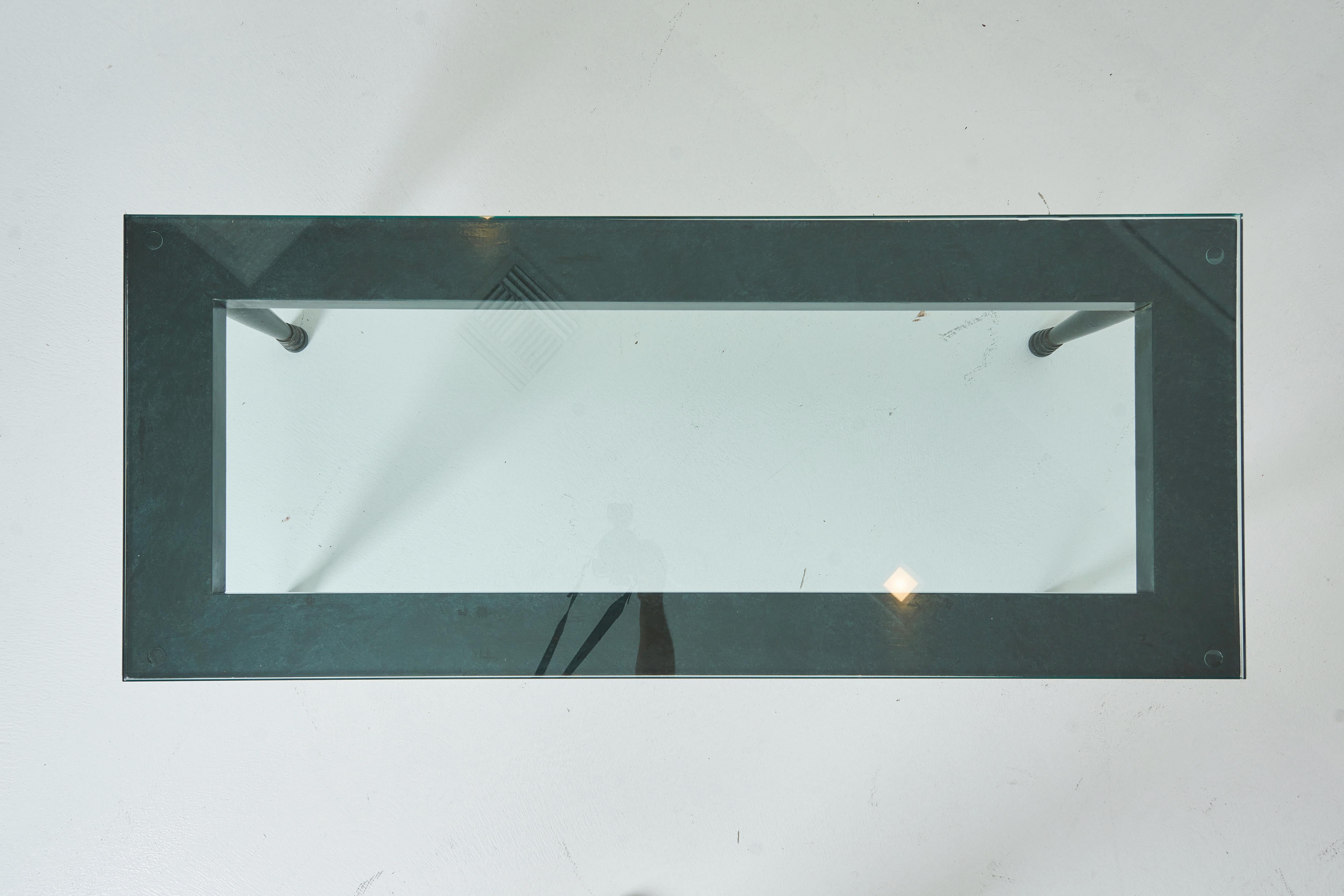 This cocktail table is a variation on an often used Haines design.  The legs are cast aluminum and fixed to wood surround that supports the glass top.  The table has a signature Haines painted finish resembling verdigris metal.  the glass top keeps