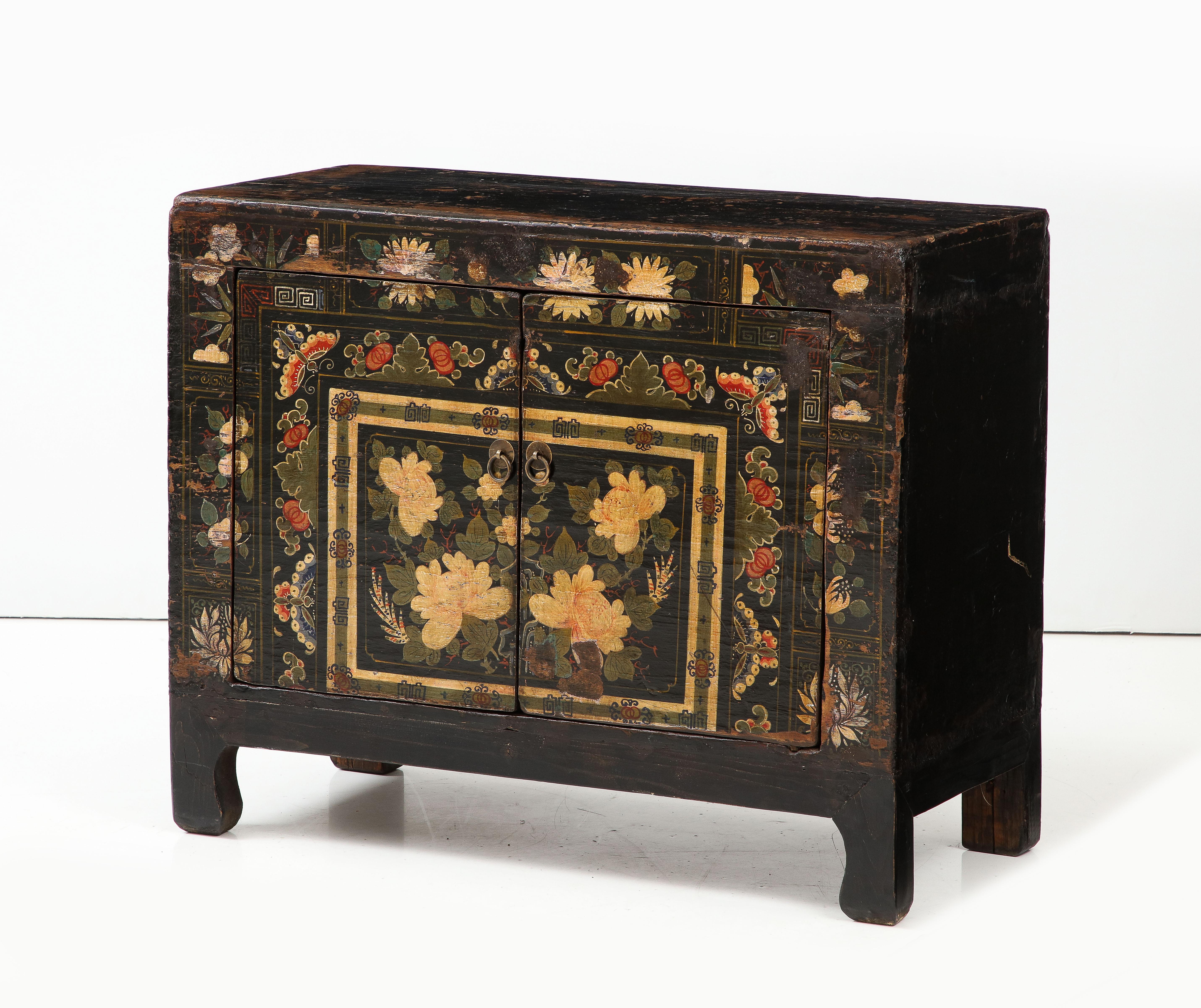 This is the kind of special piece that adds character and personality to a home.  This small cabinet is painted in a black ground color, and is beautifully decorated in a floral design in shades of gold, red and green, accented with a painted Greek