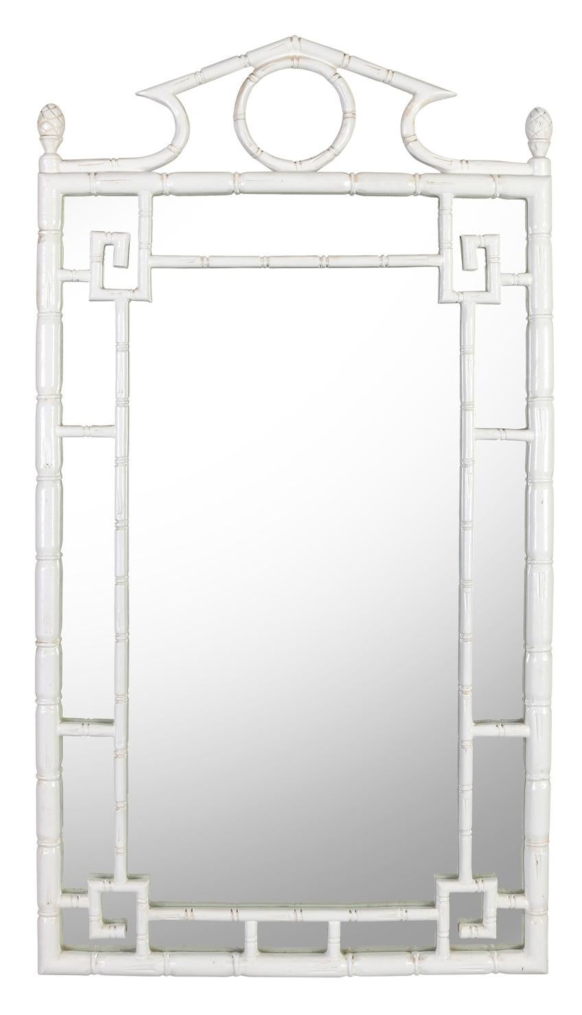 A chic faux bamboo painted mirror featuring an open fretwork frame and a lovely pediment with two simple finials. This versatile piece is well made and can add understated elegance to a room.
