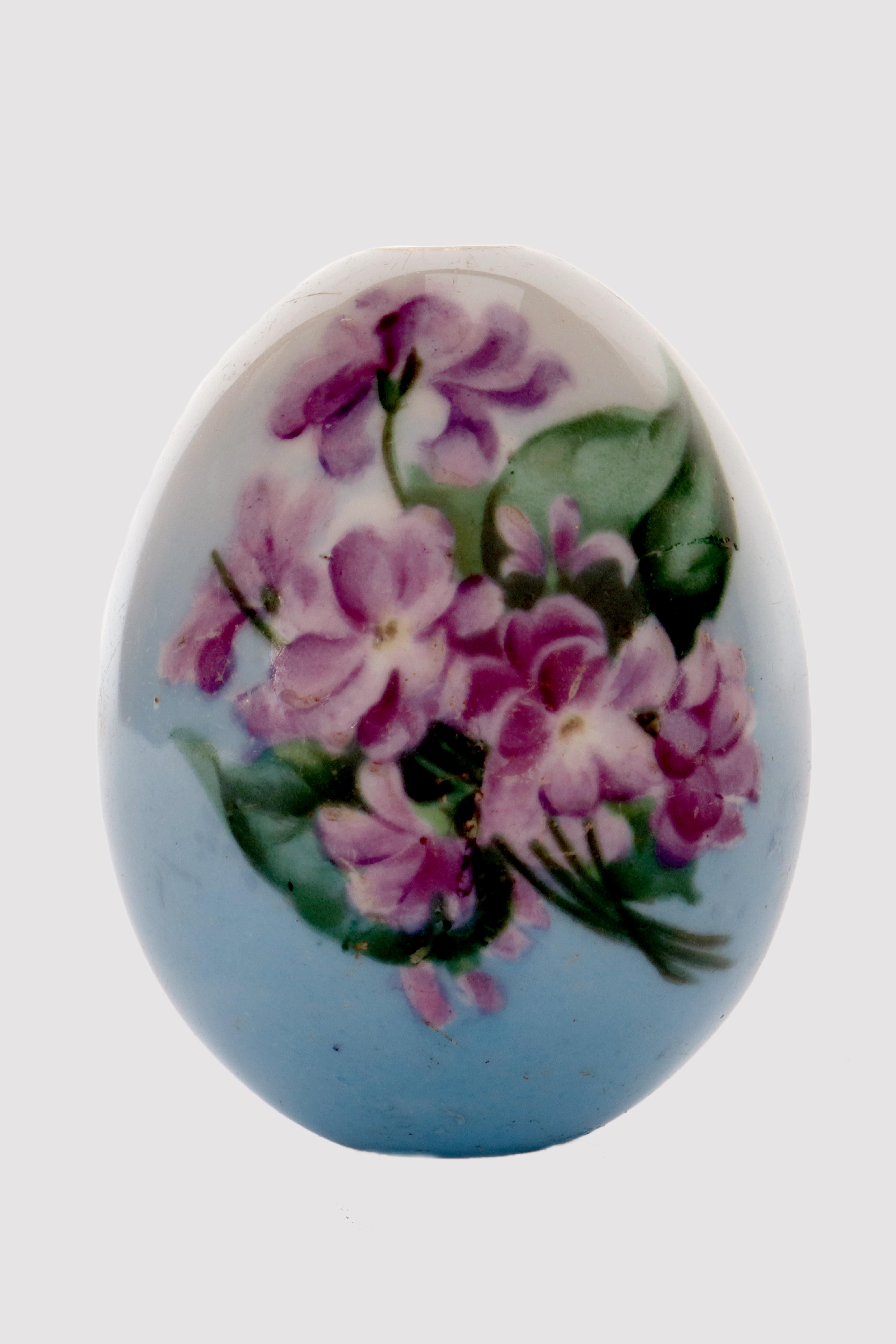 Painted porcelain Easter egg, depicting a bunch of violet flowers on one side, and the Cyrillic monogram C.R (Risen Christ) on the other side, on a blue background. Russia, circa 1890.