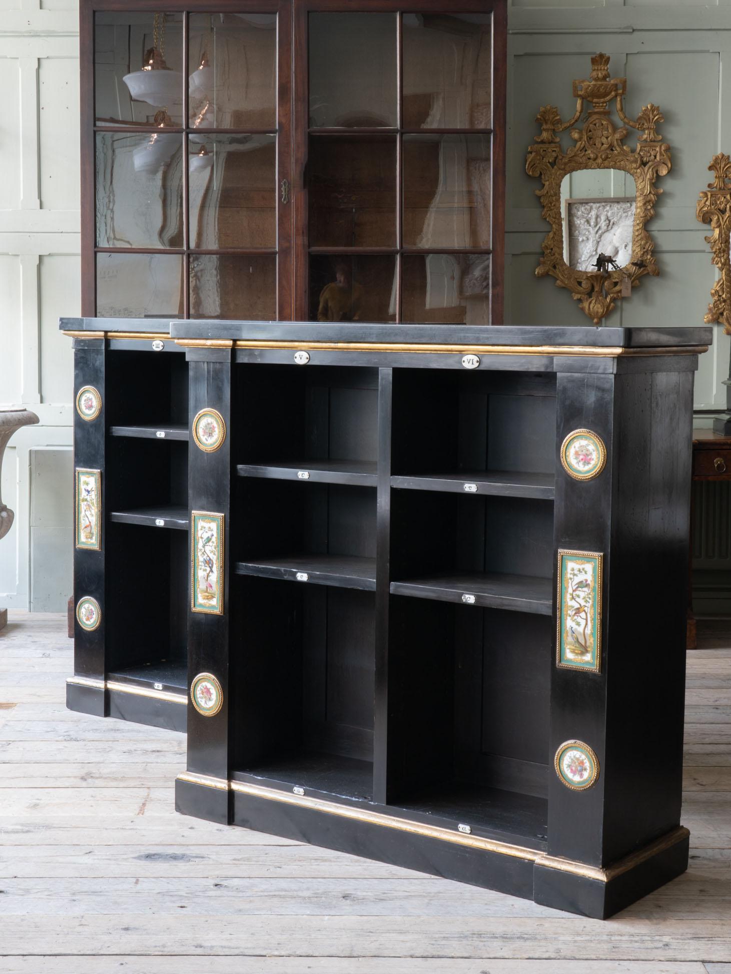 A pair of ebonised bookcases with faux porphyry slate tops.
