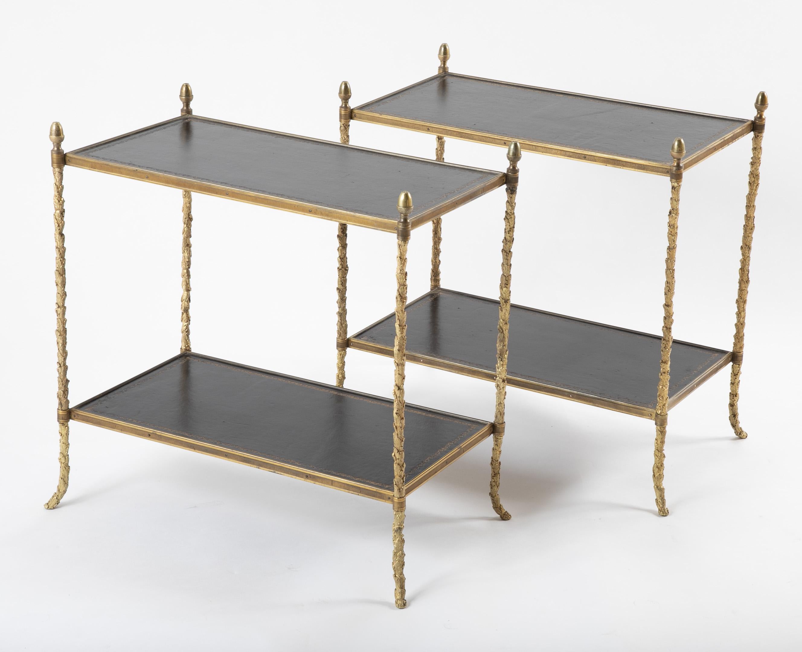 A pair of 1950s gilt bronze side tables with tooled leather tops and shelves.