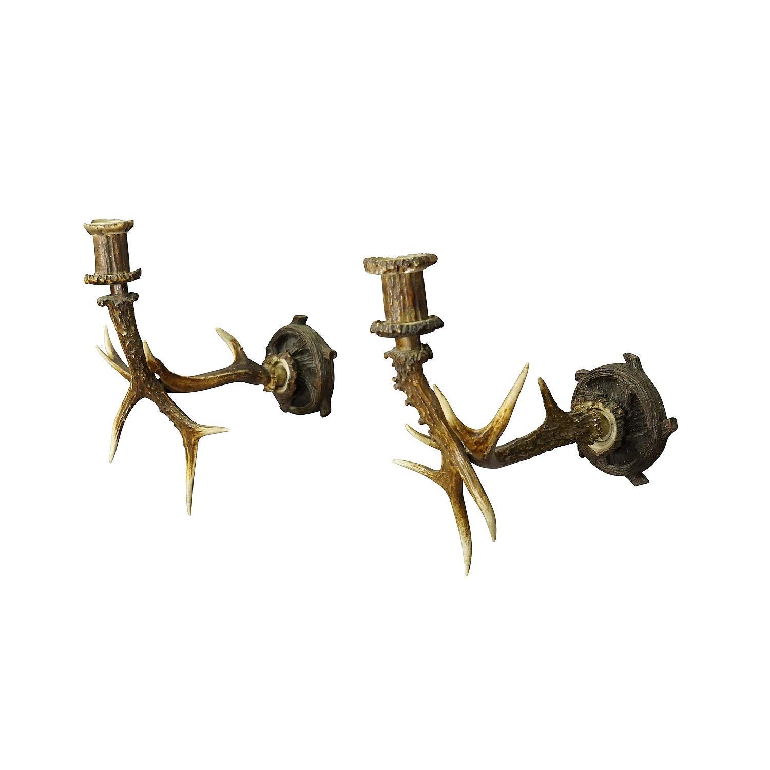 A Pair Black Forest candle sconces with Deer Horns, Germany ca. 1900

An antique pair of Black Forest sconces for candles. Each made of a pair of deer horns which are mounted on a handcarved wooden base. Spouts made of deer horns too. Executed in