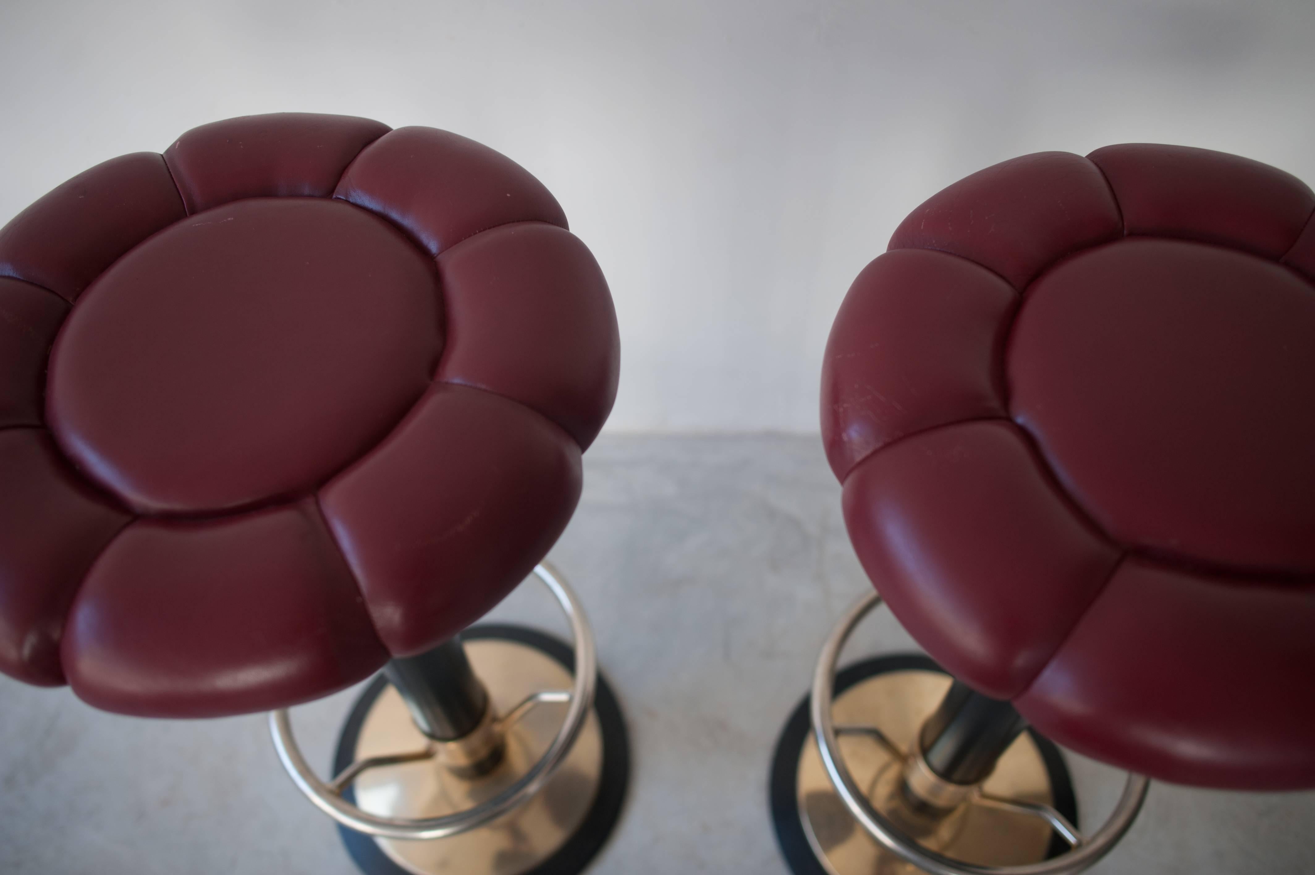 A pair of bar stools with a solid iron base gold-plated and a black lacquered tube with the support of your feet the seat is florally shaped in red leather, 1980s, Belgium.