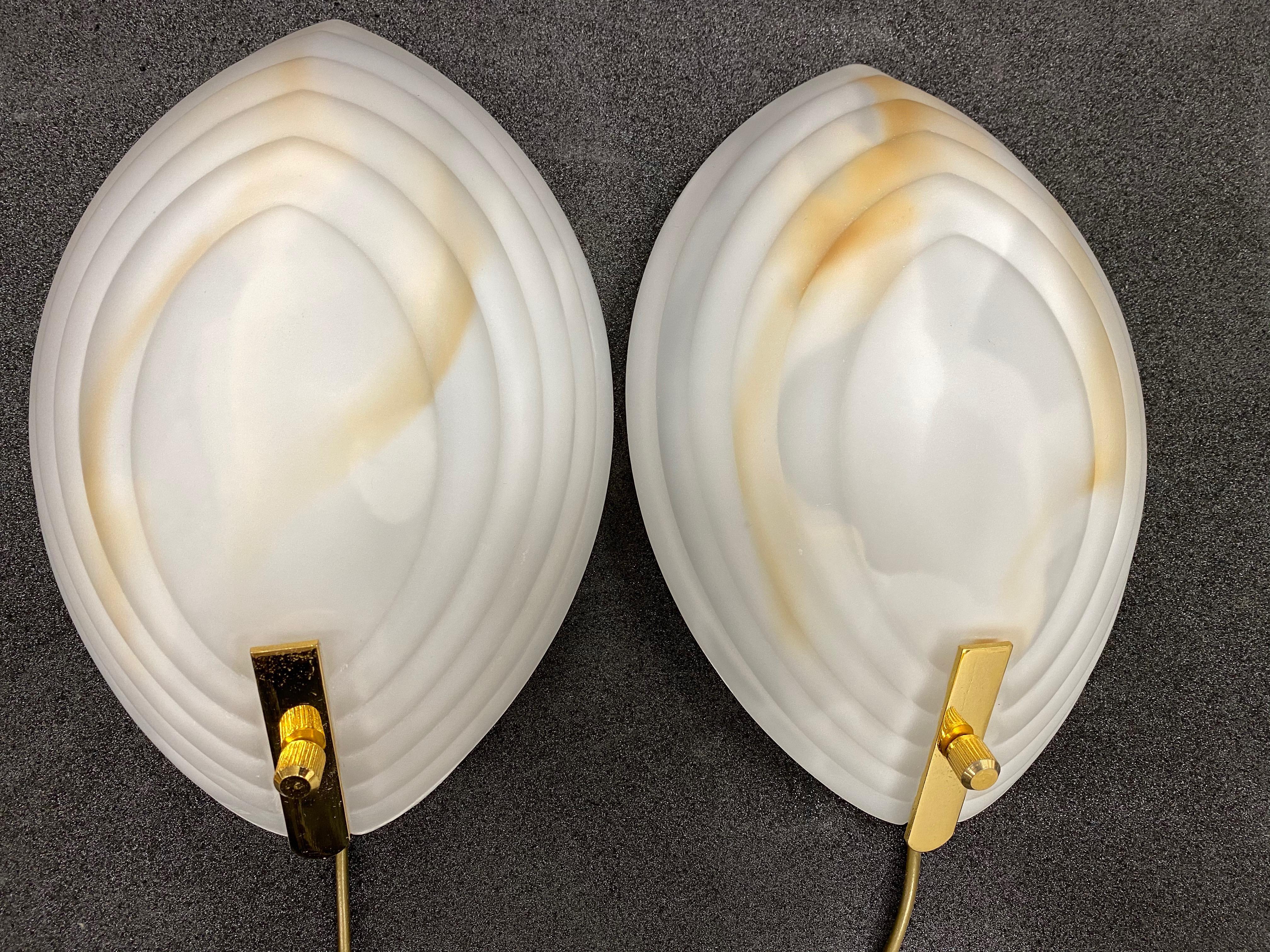Stunning pair of ribbed shaped wall lights in a high quality warm blown Murano glass. The glass bodies acquire a lovely marble tone when lit and unlit. They have white lacquered fittings and gold-plated little bars to hold the glass. Ideal for a