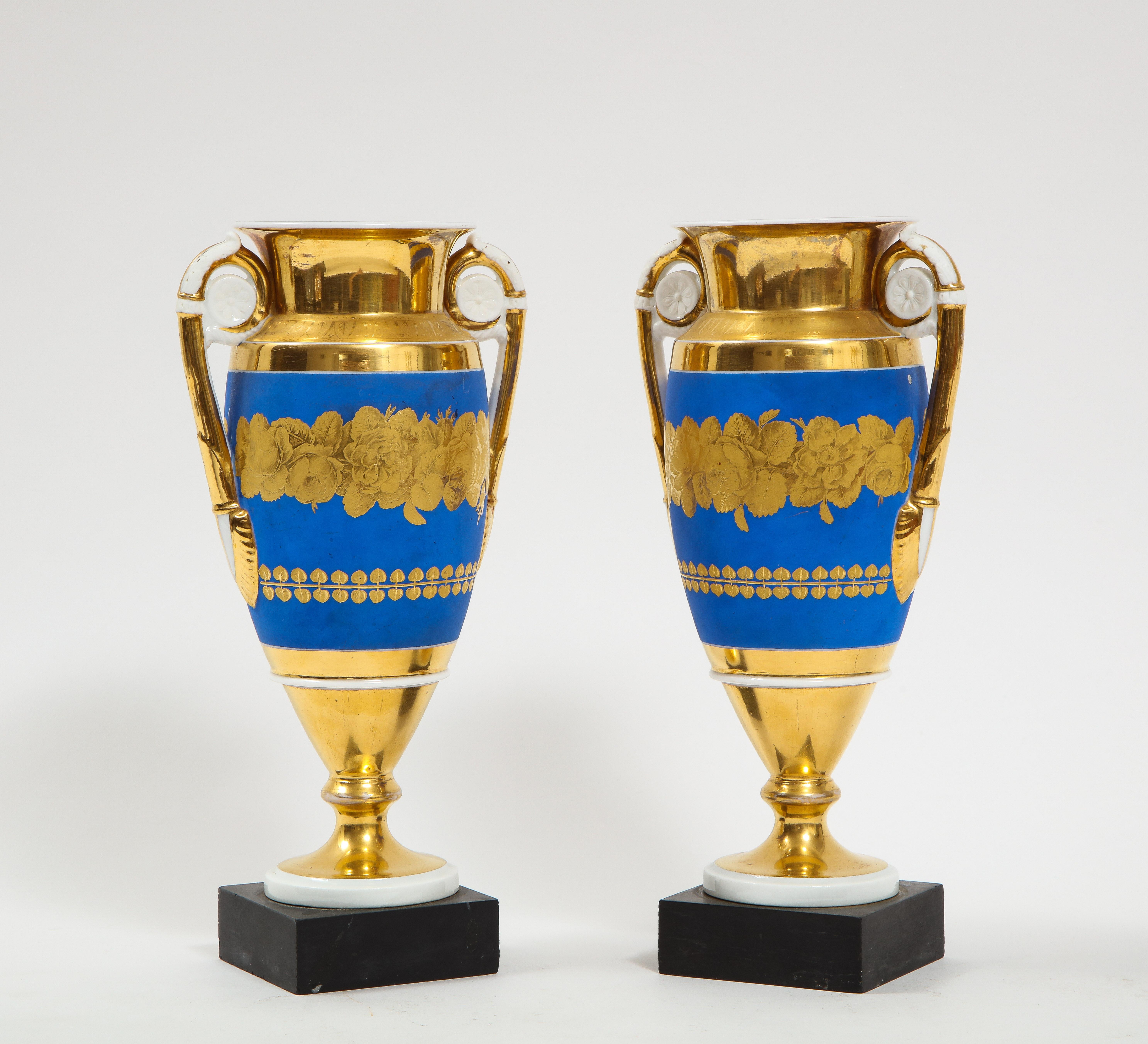 A Beautiful Pair of French 19th Century Empire Blue and Two-Tone Gold Ground Porcelain vases with White Medallion Gold Handles. Each piece is beautifully hand-painted with gorgeous light blue ground as well as two-tone matte and shiny gold flowers.